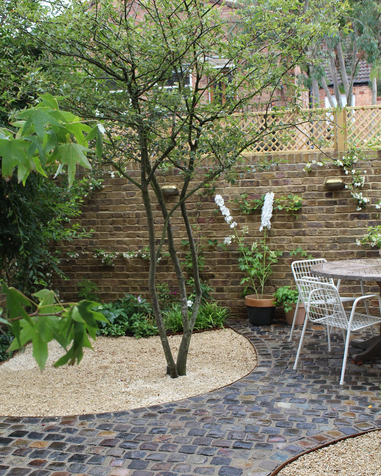 The focal point in this garden is this Amelanchier lamarckii tree, known for its beautiful seasonal changes and delicate blossoms.
We used reclaimed granite stone setts for the pathways, adding a touch of history and sustainability.
This garden is framed by walls built with London stock bricks, which have a rich history dating back to the 17th century. These bricks are synonymous with London’s architectural heritage and were traditionally made from the clay found in the Thames Basin, giving them their distinctive yellowish color. Using these bricks helps us stay true to the local character of East London.
