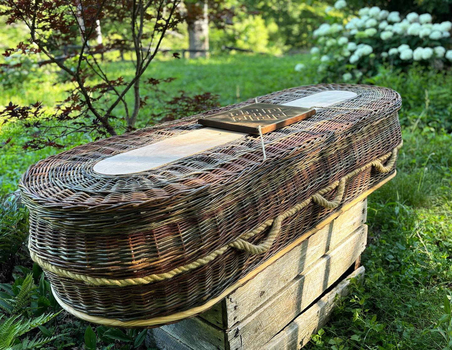 Jim’s casket. We have worked together on each step, sourcing the willow from the landscapes where he has lived his life, a center board of his favorite curly maple, a carving of the Buddhist infinity symbol by @elementalfoxcrafts on a piece of maple the Jim hand finished himself. A rope of cordage by our friend @rhombushouse from iris leaves gathered in his garden, that he and I wove into the lid together on a day out here at the farm. Yesterday it travelled at last to its new home at the foot of his bed, a mattress of cedar shavings inside creating a fragrant storage chest for blankets. And some day it will hold his body and return him to the earth, a familiar, beautiful, well-loved vessel for his familiar, beautiful, well-loved vessel.
#weavingtogether #momentomori #willowcasket #naturalburial #conservationburial #greenburial #carolinamemorialsanctuary #willow #willowcoffin #sustainability #communitycare #naturaldeathcare #communitydeathcare #cedarchest #irisgardener #appalachiangrown #wncmountains #womenownedbusiness #womenwhofarm #handwoven #willowbasketry #infinity #sophiacenterforlifestudies