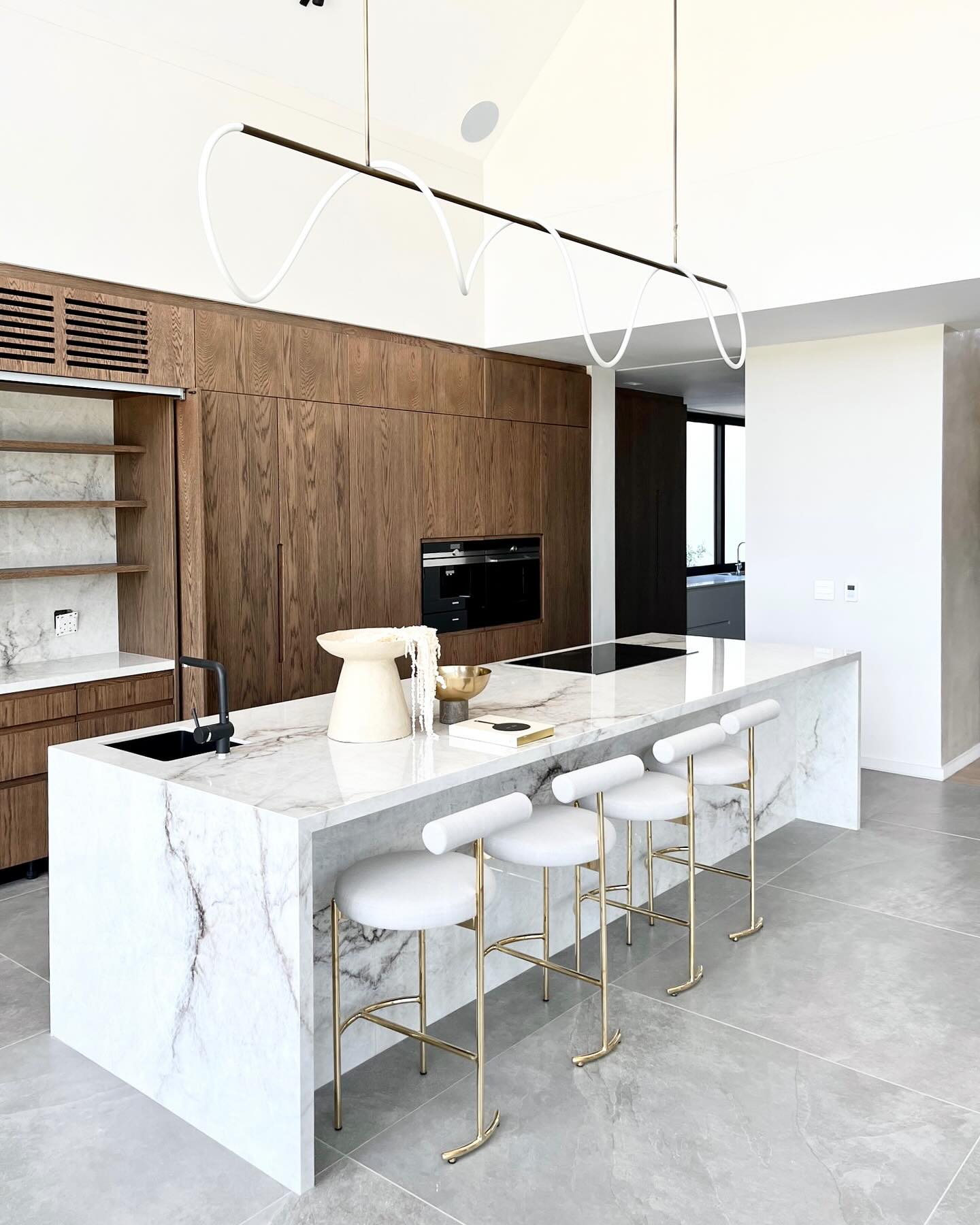 VAL DE VIE LUXURY
The spotlight is on this exquisite collab where we had the pleasure of working with Spotlight Joinery.
This stunning installation is nestled in Val De Vie and is a true testament of the luxury and modernity of this award-winning lifestyle estate.
Our team at Rock & Stone fabricated and installed this large, central island unit using Level Quarzo - top tier Italian ceramic slabs supplied by SA Stone Studio.
The island features seemingly seamless waterfall legs on either side with a full back panel on the overhang seating area and a mitre build up all around. As always, under the careful watch of an aesthetic eye, vein matching was held in high regard throughout the fabrication and installation process to create a seamless flow in all areas of application. Our team installed a high back wall panel in the coffee nook area merging effortlessly into the counter. Just left of the coffee unit is a unique picture-frame style fireplace and hearth - an elegant touch unifying the use of Level Quarzo in this space.
Level Quarzo is inspired by natural quartzite stone which boasts a crystalline structure with visual fractures creating an intertwined mosaic. It’s neutral palette consists of bright white white, soft cream, beige, and light grey with mineral impressions of brown and charcoal. It’s a perfect match for a luxurious and modern interior.
This kitchen area is brought under the spotlight with plenty of natural light highlighting the key features in this space and is further complemented by contrasting joinery in an earthy brown oak and large format tiles.
We simply love the minimalistic light fixture over the island and the gold details in the chairs. Details make a big difference in achieving the overal aesthetic of refined luxury.
All in all an incredible artistic display throughout and we are proud to share this project with you. Well done to all involved in bringing this space to life.
@spotlightjoinery @sastonestudio