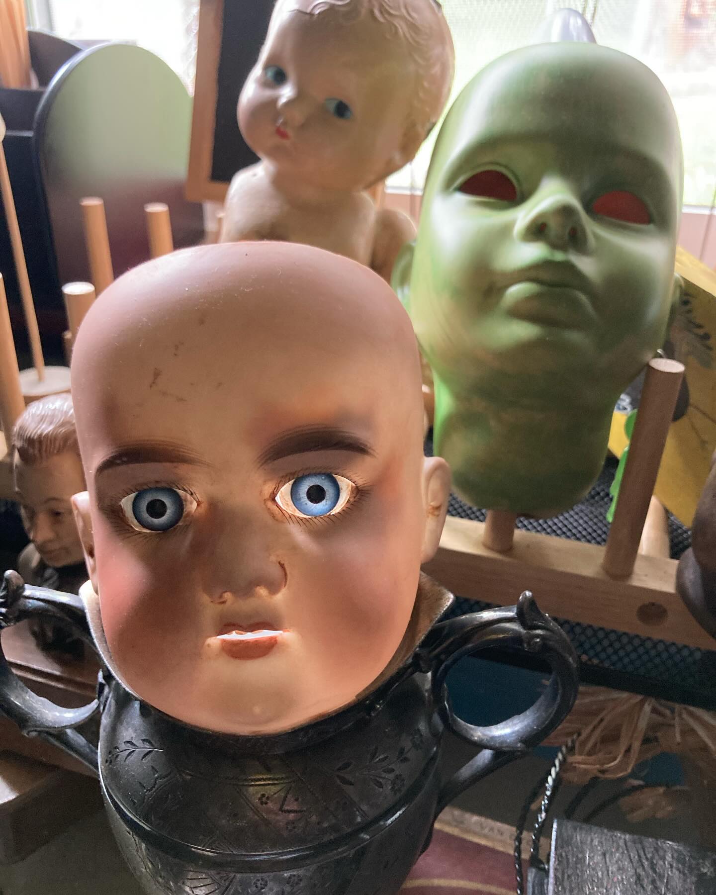 Walked into my studio today and this was staring back at me! The sunlight was shining in the top of the head which illuminated the glass eyes, which freaked me out just a lil’ bit! The other creepy thing is it’s mounted on an urn dated 1893 that has the name “Bess”inscribed on it. A work in progress left on the bench, until I start creating again in the fall. 🫣😅👀#dollheads #creepydolls #dollparts #dollart #antiquedolls #haunteddolls #assemblage #foundobjects #crooksycreations