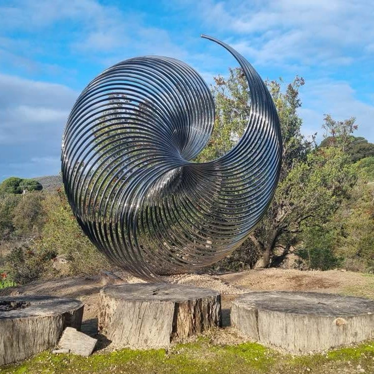 Last week, we were proud to commission our second major installation of 2025, thanks to a partnership between sculptural artist George Andric & generous benefactors Roger & Helen Salkeld.
George's stunning, glittering work 'Ellipsis' is an interpretation of the evolutionary processes in nature, and the patterns that emerge as a result... simple elements arranged to create a complex form.
The Kangaroo Island Sculpture Trail exists because of the passion & generosity of so many members of our community. Helen Salkeld captured it beautifully at the commissioning ceremony:
"The Arts play such an important role in any community, frequently surviving largely with the assistance of private philanthropy, through donations of both time and money, large and small. This Sculpture Trail is the epitome of that community involvement. Roger and I have been fortunate to have our own lives enriched by theatre, music, art and sculpture ...... we felt we couldn’t pass up the opportunity to finally contribute something to the community we love, so this is our gift to Penneshaw and to the island on behalf of the FWH Foundation."
Come for a wander on the trail soon to see this beautiful new installation. And if you would like to support future works via a tax-deductible contribution - large or small, visit our website via link in profile.