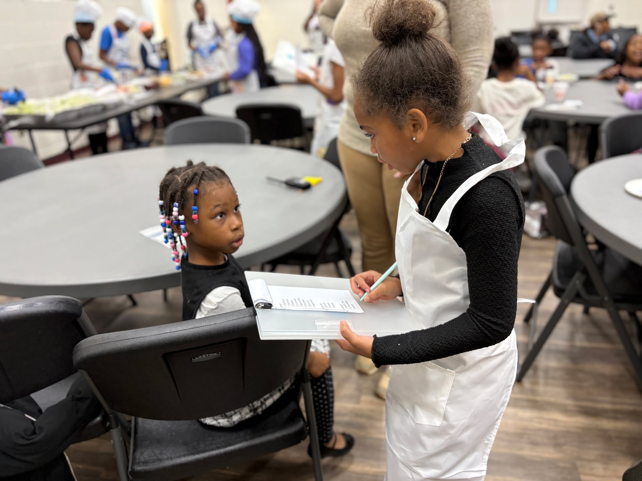 Introducing Soulful Eats, a restaurant that opened its doors for one night only yesterday at Peter Paul. Led by Ms. Bailey, the 4th- and 5th-grade students worked both the back and front of the house. The servers waited on customers (our younger elementary students) and relayed orders to the kitchen, where chefs assembled salads and worked together to keep the space organized and clean.
Meanwhile, at a trail mix assembly station, servers helped the younger kids create customized snacks to take home. A third station invited students to build healthy meals using paper food, balancing their plates according to dietary guidelines.
This role-play engaged a wide range of skills, including communication, time management, organization, graciousness, and patience. The older kids demonstrated a strong work ethic while having fun. Food critics give Soulful Eats five stars! See more photos on our flickr: https://flic.kr/s/aHBqjCBXhx
#SoulfulEats #StudentChefs #HandsOnLearning #HealthyHabits #FutureLeaders #PeterPaulCommunity #LearningThroughExperience #KidsInTheKitchen #TeamworkInAction #CreativeLearning