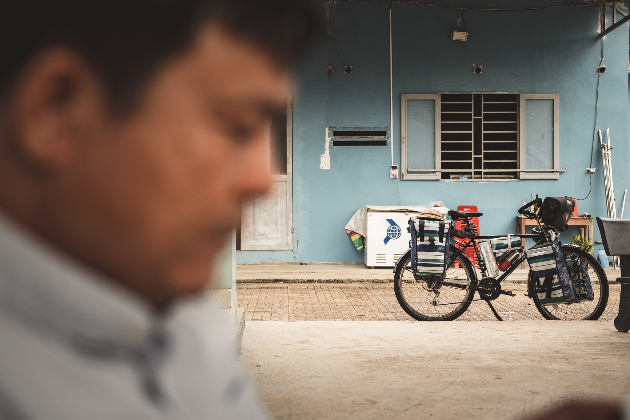 The Hidden Side of Humanity: the Night
The story almost always begins the same way. The light softens, the sun drops its last golden strokes on the countryside.
In my hesitant Vietnamese, I ask:
“Do you know a safe place where I could pitch my tent tonight?”
A simple question — and yet the boldest one of the whole journey.
Because it opens a door: the door to the unknown, to spontaneity, to everything that might unfold once the day has ended.
During the day, I observe. At night, I enter.
Night becomes the shared space where encounters deepen, where understanding grows finer.
Most of the time, the answer comes quickly, offered with a smile:
“Of course, at my place, just here!”
So I say yes.
I follow the path I chose: I step into people’s lives for an evening, with curiosity, respect, and gratitude.
And every night takes on a completely different shape, always unexpected:
A family living inside a post office inflating a mattress for me in their children’s room.
A little girl insisting that I sleep next to her in her bed.
A priest welcoming me with immense gentleness.
Buddhist nuns laying out a mattress for me in their monastery.
Another family pushing their furniture aside to hang a mosquito net in the middle of their home.
And countless other scenes unlike anything I could anticipate.
Yet through all these stories runs the same thread: the joy of meeting, the pleasure of sharing.
Food passed around, sometimes alcohol, always laughter. Kindness and generosity as a common language—a quiet cement that builds trust.
Because for me, the real journey doesn’t happen on my bike during the day, but at night, with the people who welcome me. That’s where humanity reveals its brightest light.