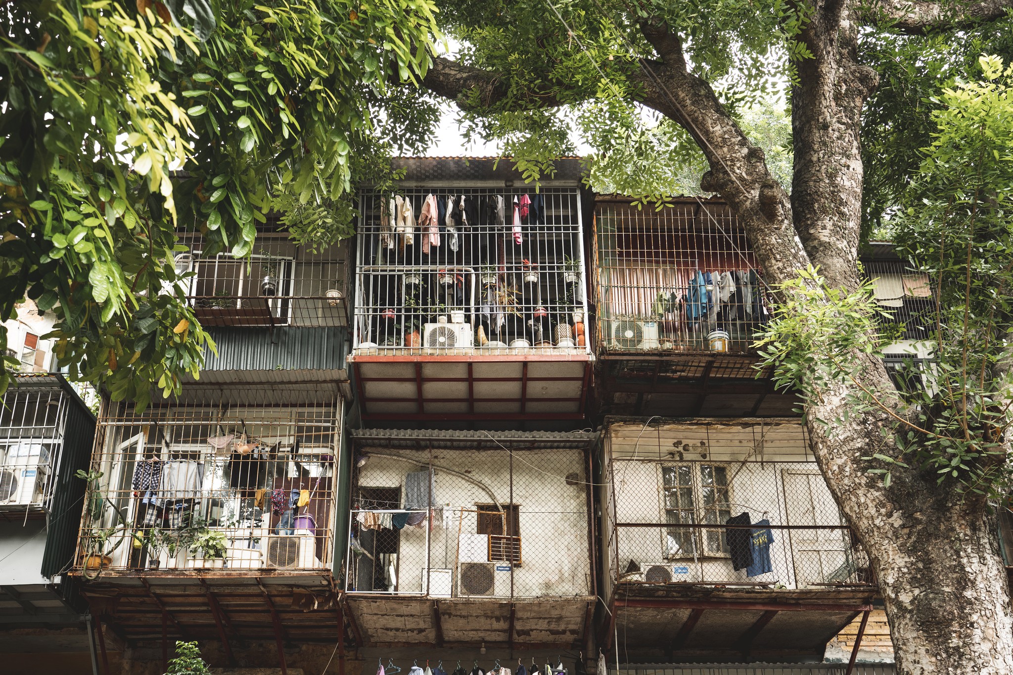 Hanoi’s Khu Tập Thể: a vernacular urban heritage in transformation
An ordinary heritage, crossed by ordinary lives. Two long, low housing blocks—three or four stories high—embrace a shaded courtyard where children play, where elders stretch in the morning light, where cafés spread their little plastic tables, and the barber hangs his mirror from a tree.
Built between the 1960s and the 1990s, the Khu Tập Thể emerged in post-war socialist Vietnam, heavily influenced by Soviet urban models. They were designed to respond to a housing shortage while embodying an ideal of social equality. Courtyards, staircases, and sometimes shared kitchens or bathrooms: communal spaces were everywhere.
Over time, these buildings began to shift. Informal extensions appeared—gridded metal additions jutting out in mid-air, often made from scavenged materials. Nicknamed “tiger cages” (chuồng cọp), they reshaped the façades and horizontally densified the blocks. But these interventions are not mistakes; they’re adaptive responses, blending local know-how, pragmatism, resourcefulness, and creativity. A living architecture, constantly in the making—outside official frameworks, by the inhabitants and for the inhabitants. A form of popular inventiveness, an intuitive way of inhabiting and transforming the city.
Here, I finally feel life. A village life, beating inside a metropolis.
Today, this singular architecture is under threat from the pressure of a rapidly expanding Hanoi.
And yet, I like to believe that this spontaneity and everyday creativity could inspire contemporary practice — reminding us that a city is, above all, a space of sharing, adaptation, life, and invention.
Thank you again @kechocollective and @tuean._h for showing me this unseen and deep part of Hanoi.
