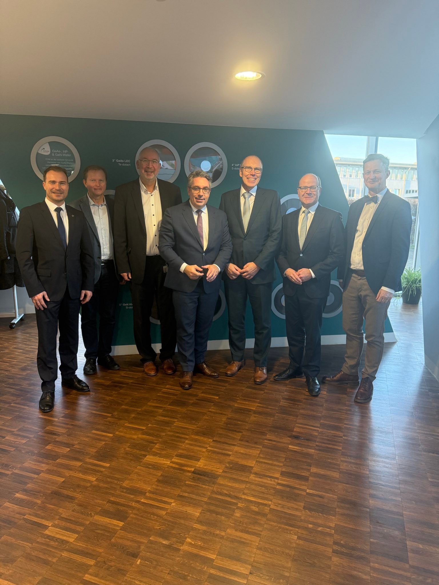 Wie kann die künftige Rohstoff-Lieferkette eines weltweiten führenden Halbleiter-Unternehmens nachhaltig gesichert werden, dass war heute Kernthema bei der Freiberger Compound Materials GmbH. Es war gut, dass der Parlamentarische Staatssekretär Stefan Rouenhoff (Bundesministerium für Wirtschaft und Energie), Europaabgeordneter Oliver Schenk, der Chef der Sächsischen Staatskanzlei Andreas Handschuh, sowie Vertreter des Sächsischen Staatsministeriums für Wirtschaft, Arbeit und Verkehr, und weitere Entscheidungsträger von Bund und Land heute deswegen zu Gast in unserer Silberstadt Freiberg waren.
Im Mittelpunkt des Austauschs stand – nach einem Unternehmensrundgang – die Frage, wie die Anforderungen an eine verlässliche Rohstoffversorgung für heimische Hochtechnologieunternehmen langfristig erfüllt werden können – ein zentrales Thema für die Landes-, Bundes- und Europapolitik.
Als führender Hersteller von Verbindungshalbleitersubstraten für die Mikro- und Optoelektronik produziert FCM Materialien wie Galliumarsenid (GaAs), Indiumphosphid (InP) und Galliumnitrid (GaN). Diese sind unverzichtbar für moderne Anwendungen – von Smartphones über Mikro-LED-Technologien bis hin zu Infrarotsensoren für autonomes Fahren. 📱🔋👨💻⌚️
Ohne die Spitzenhalbleiter von FCM würde so gut wie kein Smartphone weltweit funktionieren. Unsere Technologien stehen für Innovation „Made in Freiberg“ – und genau das soll auch in Zukunft so bleiben.
Der heutige Besuch gibt mir Mut, dass die Beteiligten ihre Aufgabe ernstnehmen und die Unternehmen genau dabei unterstützen. Denn eine gesicherte Rohstoffversorgung ist der Schlüssel für Wettbewerbsfähigkeit, Wertschöpfung und die Zukunft unserer heimischen Industrie. Es wird die Arbeitsplätze der Zukunft stärken und das finanzielle Fundament unser Stadt stärken. ⚒️🩶📈