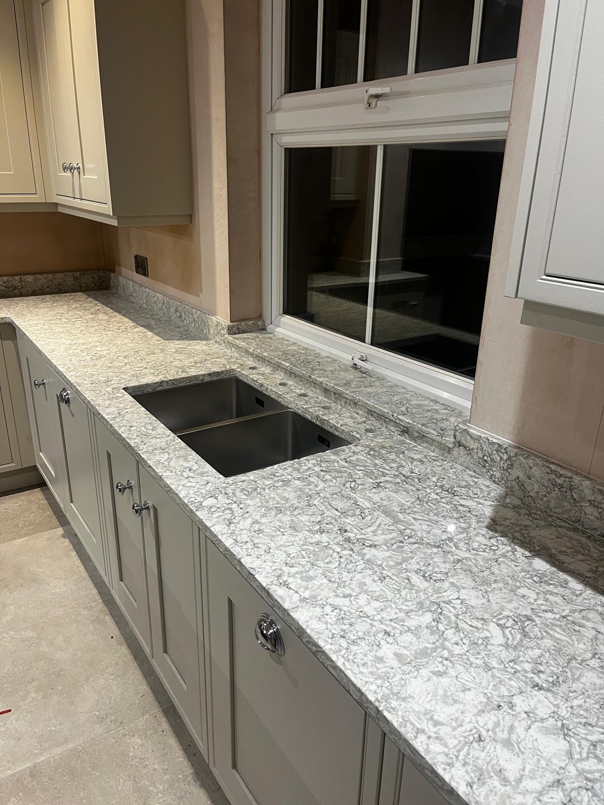 Qstone Arctic Storm worktops and island with ogee edge detail, clad panels and cook shelf inside cooker recess and window sill, fitted in Helsby