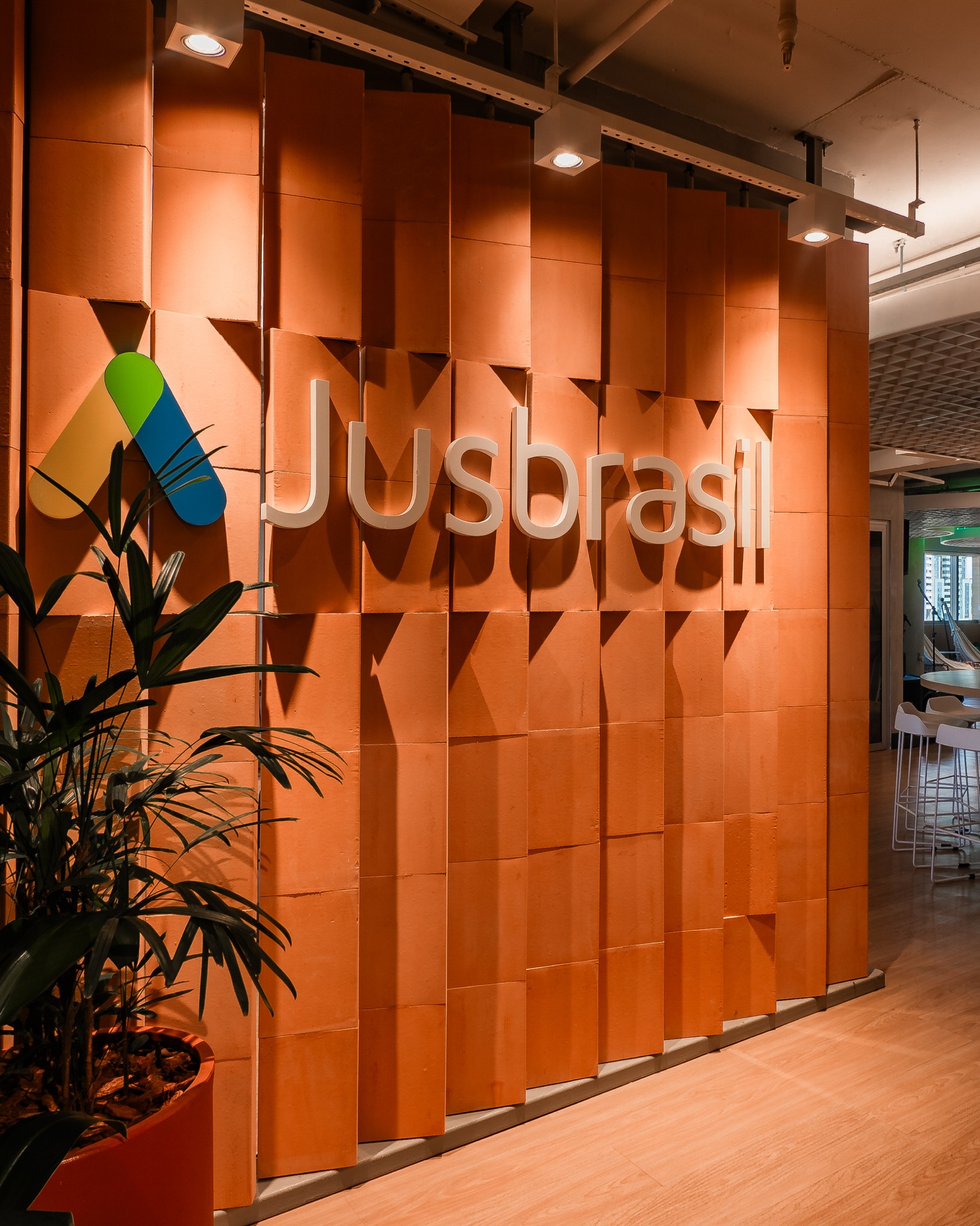 No projeto corporativo do JusBrasil, entregue em Fevereiro de 2025, existia uma grande demanda de conforto acústico que envolvia reduzir o ruído para permitir o estado de flow e também a privacidade em diversos ambientes. Cada decisão acústica surgiu de forma planejada e alinhada com as questões estéticas proporcionar ambientes produtivos e adequados a rotina da equipe.
Havia um desafio muito específico: o escritório possui um espaço de descompressão com um palco para apresentações, um ambiente dinâmico, projetado para eventos internos, música e interação. Para que essa área funcionasse de forma plena e sem interferir nos ambientes adjacentes, foi necessário um isolamento mais robusto e controle da reverberação em todas as frequências.
Apesar da demanda técnica, a arquitetura estava atendendo a demanda do cliente de evitar uma estética “fria” típica de ambientes corporativos. A solução foi trazer materiais naturais e acolhedores, que equilibrassem performance acústica e identidade visual. Madeira, cortiça e vegetação passaram a trabalhar juntas como elementos arquitetônicos e funcionais para absorver o som, suavizar reflexões sonoras e criar uma atmosfera mais humana.
O resultado é um escritório que soa tão bem quanto aparenta, um ambiente capaz de garantir privacidade, reduzir o stress, sustentar momentos de descontração e, acima de tudo, promover bem-estar sem abrir mão da personalidade.
Projeto: @gam_arquitetos
Projeto Acústico: @audiumoficial @deborabarretto @peuresende @arqcristhiannascimento