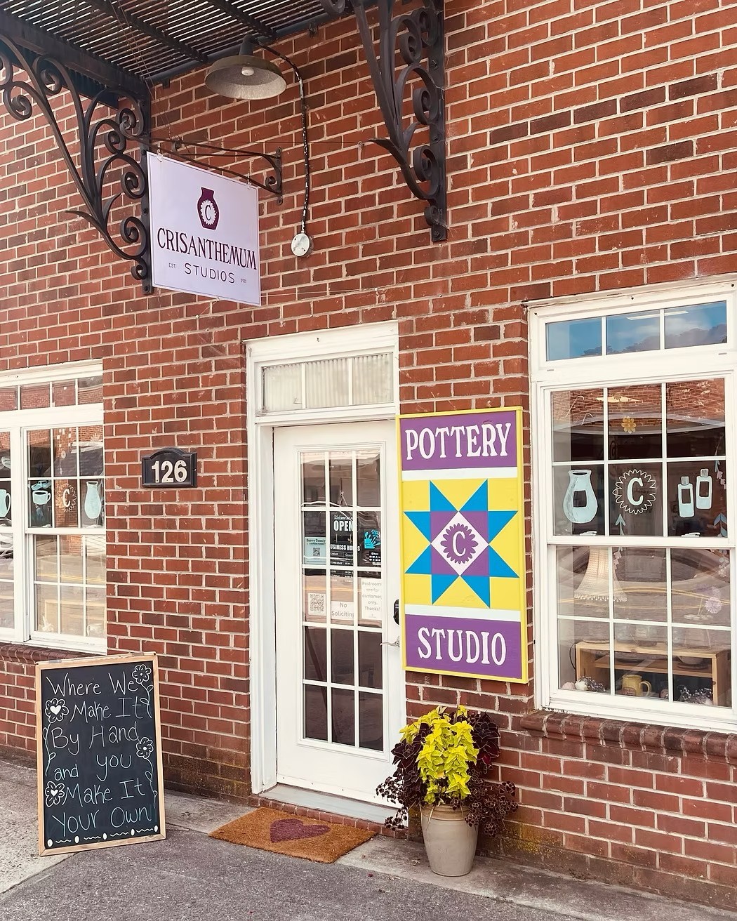 As the year comes to a close, I find myself sitting with a feeling that’s hard to put into words — a mix of gratitude, pride, disbelief, and deep appreciation.
This year marked our first year on Main Street in downtown Pilot Mountain, and what a year it has been.
Crisanthemum Studios didn’t just open its doors — it found its people.
From the beginning, this space was imagined as more than a pottery studio. It was meant to be a place where creativity feels accessible, people feel welcomed exactly as they are, and handmade work becomes part of everyday life. Watching that vision take shape has been one of the greatest honors of my life.
And it happened because of you.
This year, we welcomed so many first-time glazers — people who walked in curious, sometimes nervous, unsure if they were “creative enough.”
They left smiling. They left proud. They left saying, “Wow… I did that.”
Whether it was a mug, bowl, spoon rest, or keepsake, each piece carried more than color — it carried confidence, joy, and a moment of pause.
You trusted us with your time, creativity, and stories — and that trust means everything.
This year brought milestones we’re proud of, including being recognized as an NC Destination Business. But the real milestones were the packed tables, quiet conversations, families who made glazing a tradition, and visitors who found us by chance and left feeling connected.
There is something truly special about being a small business on Main Street in Downtown Pilot Mountain. This town welcomed us with open arms — neighbors, fellow business owners, and locals who proudly bring others to “their” pottery studio.
Everything we do comes back to one belief: handmade belongs in everyday life.
Our pottery is meant to be used — for morning coffee, shared meals, quiet moments, and meaningful gifts.
This studio exists because of you.
Thank you for choosing handmade. Thank you for choosing local. Thank you for choosing creativity, connection, and care.
This first year on Main Street has been more than we could have imagined — and it’s only the beginning.
With muddy hands and deep gratitude,
Cris the Potter 💜