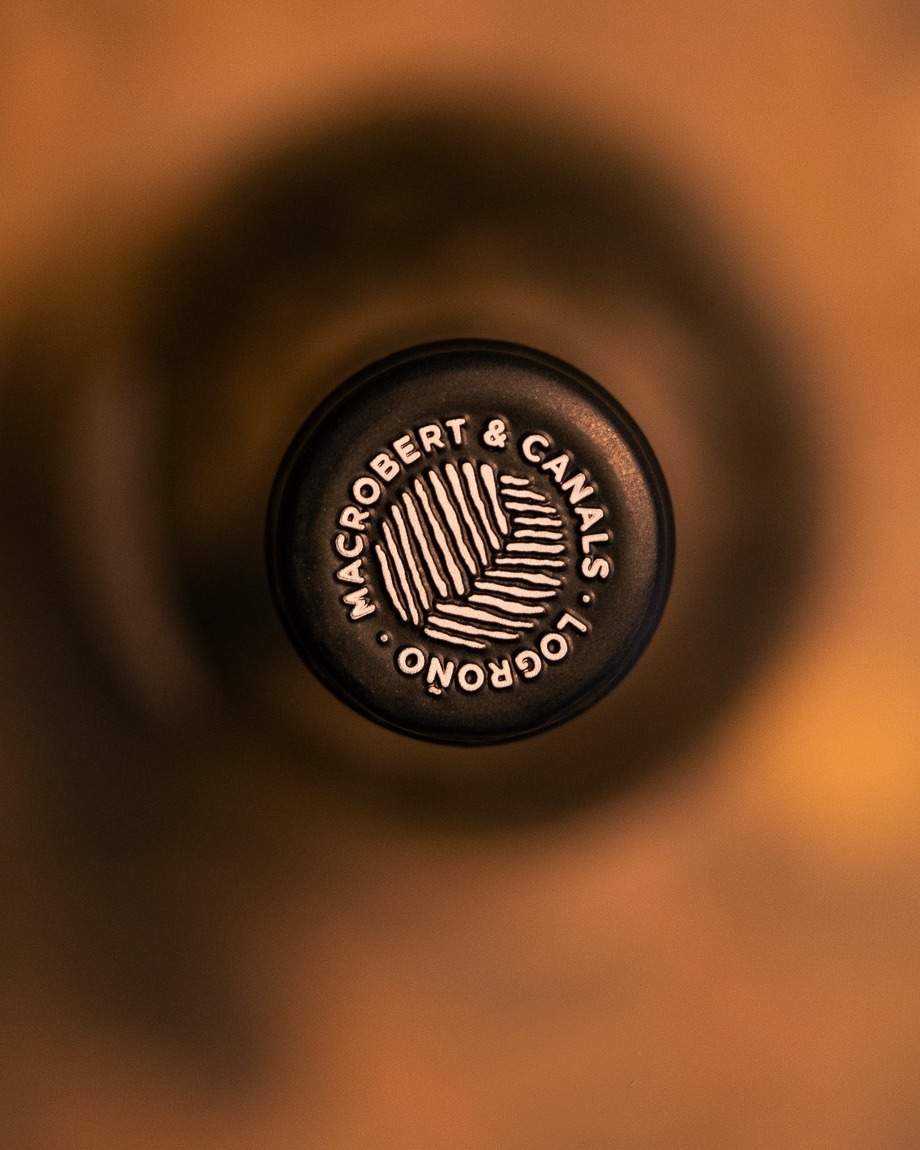 MacRobert & Canals es una bodega ubicada en Logroño dentro de la D.O.Ca. Rioja, nacida de la integración del enólogo sudafricano Bryan MacRobert en la familia Canals, con décadas de arraigo en Rioja. Se enfoca en parcelas de bajo rendimiento, viñas viejas y suelos diversos. Su producción es limitada, manual y de alta calidad, reflejando la diversidad climática y edáfica de la Rioja con un enfoque sostenible y respetuoso con el medio ambiente.
La añada 2024 ha estado marcada por una climatología equilibrada que permitió maduraciones lentas y precisas, preservando frescura, tensión y expresión varietal. En este contexto nacen Paraje de la Virgen y Barranco del San Ginés, dos vinos de parcela que reflejan con fidelidad el carácter de sus viñedos históricos, la influencia de los suelos calizos y una viticultura respetuosa.
🍷 Paraje de la Virgen: Procede de un viñedo singular de menos de una hectárea en Lanciego, plantado en 1920, con mezcla tradicional dominada por Tempranillo. Los suelos calcáreo-limosos y la altitud superior a 500 m permiten una maduración lenta y equilibrada. La elaboración artesanal y la crianza de unos 12 meses en roble francés dan lugar a un vino elegante, fresco y preciso, con fruta madura, taninos finos y clara expresión del terroir.
🍷 Barranco del San Ginés: Nacido de un viñedo histórico de 1935 en Laguardia, situado en laderas y terrazas de suelos calizos muy pobres, combina Tempranillo con variedades tradicionales. La altitud y la orientación aportan profundidad y equilibrio, mientras que la elaboración minuciosa y la crianza prolongada en barrica y botella resultan en un vino estructurado, complejo y con gran capacidad de guarda, fiel reflejo del carácter del viñedo.
🌐 Descubre Paraje de la Virgen y Barranco del San Ginés de MacRobert & Canals en nuestra vinoteca y distribuidora, y también en nuestra página web.