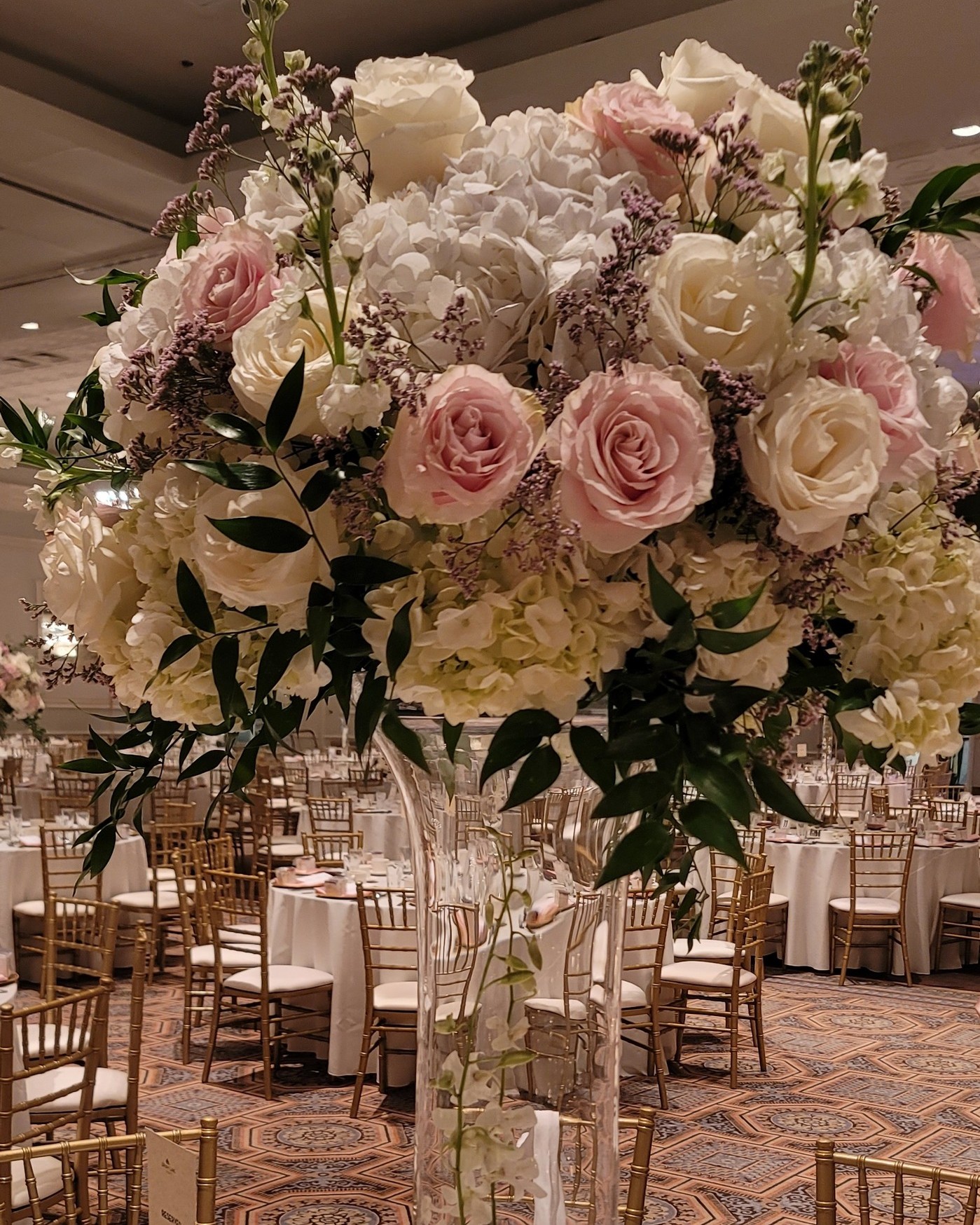 This breathtaking tall centerpiece is pure romance - soft blush roses, lush white hydrangeas, and delicate greenery coming together in a timeless, airy design. Crafted with fresh flowers, each bloom adds natural beauty, movement, and fragrance to the room 🌸 Perfectly elegant, beautifully luxurious, and ideal for couples who want a show-stopping statement that feels organic and unforgettable. This is the kind of centerpiece that turns heads and sets the tone for an extraordinary celebration.✨