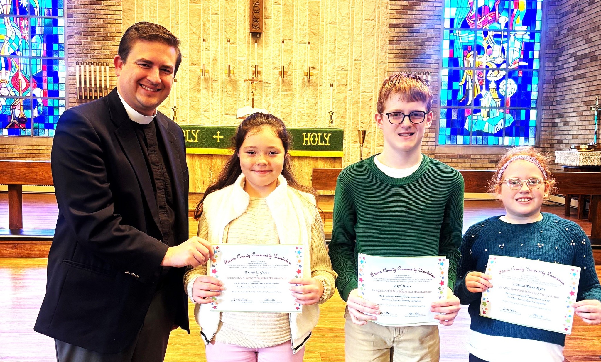 Pictured: Pastor Zach Oedewaldt, Zion Lutheran Church (Decatur) is shown presenting certificates to the three Lyncoln Ann Hess Scholars. These are Emma Garza, age 10 (4th Grade), Axel Myers, age 11 (6th Grade), and Lisuana Myers, age 8 (2nd Grade).
The Lyncoln Ann Hess Memorial Scholarship Fund was established in 2013 in memory of Jesse and Alicia Hess’ daughter, Lyncoln, who was just seven weeks old when she grew her angel wings. This scholarship, awarded to current or registered students at Zion Lutheran Church in Decatur, may be awarded to students in K- 8th grades and is to be applied to the recipient’s tuition.
Alicia Hess said that the family would like to give children a childhood that they were never able to give Lyncoln. This scholarship is managed by the Adams County Community Foundation.