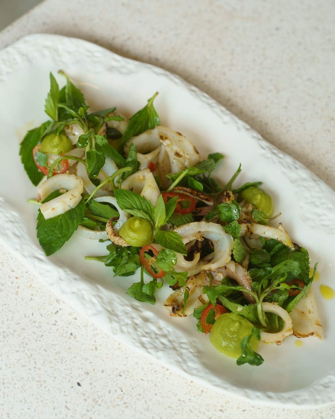 Salad Mực Nướng & Sốt Kem Bơ - Một bản phối thật “phiêu” 🥑
Mực nướng than hoa xém cạnh, đặt nhẹ lên trên nền sốt kem bơ sánh mịn.
Vị khói nồng nàn tan ngay trong cái béo ngậy, điểm xuyết chút thảo mộc dậy hương. Không mix vị chua cay như thông thường mà là sự hòa quyện chậm rãi của mực tươi ngọt và sốt bơ tan nhẹ bên đầu lưỡi.
Đủ lạ để tò mò, đủ tinh tế để phải lòng ngay lần đầu chạm đũa.
__________________
Grilled Squid Salad With Herbs & Avocado Cream – A soulful pairing 🥑
Char-grilled squid with seared edges, resting lightly on a bed of velvety avocado cream.
Smoky notes melt instantly into the creamy richness, accented by a touch of aromatic herbs. Far from the usual spicy-sour mix, this is a slow harmony where the fresh sweetness of the squid meets avocado melting softly on the tongue.
Intriguing enough to spark curiosity, refined enough to fall in love at first bite.
____
𝗦𝗔𝗜𝗚𝗢𝗡𝗘𝗦𝗘 𝗘𝗔𝗧𝗘𝗥𝗬
129A Trần Hưng Đạo, Dương Đông, Phú Quốc
Tel 0938059650
#saigoneseeatery #phuquoc