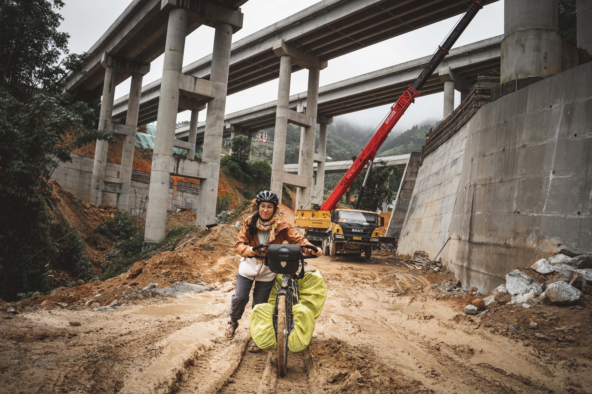 Sud Yunnan - le verso de la carte postale
Sur un territoire grand comme l’Allemagne, le Yunnan abrite 25 des 55 minorités ethniques officiellement reconnues en Chine. Des cultures façonnées par les reliefs, à la croisée des mondes d’Asie du Sud et des hauts plateaux tibétains.
Des langues, des rites, des cuisines, des systèmes d’écriture parfois uniques. Des architectures vernaculaires enracinées dans la matière - la terre, le bois. Une densité culturelle vertigineuse - sur le papier.
Et pourtant. Jamais je n’ai vu une folklorisation aussi massive, aussi brutale. Des villes entières transformées en parcs à thème. Des centres commerciaux à ciel ouvert plaqués sur des centres historiques. Chaque vieille ville scénographiée selon “son” ethnie locale, réduite à un décor.
En quelques années, Dali, Lijiang, Shangri-La ou Xishuangbanna ou sont devenues d’immenses studios photo. Des flots de touristes — majoritairement Han, venus des grandes métropoles — louent des costumes dits “traditionnels”, posent à cheval, perche à selfie levée, projecteurs braqués sur des ruelles reconstituées. Les haut-parleurs hurlent, les enseignes clignotent. L’illusion est totale.
Mais que reste-t-il derrière la mise en scène ?
Quand une culture minoritaire devient marchandise esthétique, expérience à consommer — ne risque-t-elle pas de se dissoudre dans sa propre caricature ?
Et puis il y a les villages. À l’opposé du spectacle : gris, silencieux, parfois résignés, baignés d'une grande lassitude. Traversés par des infrastructures tentaculaires — routes, ponts, barrages — des milliers de kilomètres d’asphalte, et d’autres encore en chantier, que les cartes n’ont pas le temps d’imprimer et dans lesquels je patauge, la boue jusqu'aux chevilles.
Entre ces deux réalités, je pédale.
À essayer de comprendre ce qui disparait dans cette transformation hors normes.
👇 English version in the comments