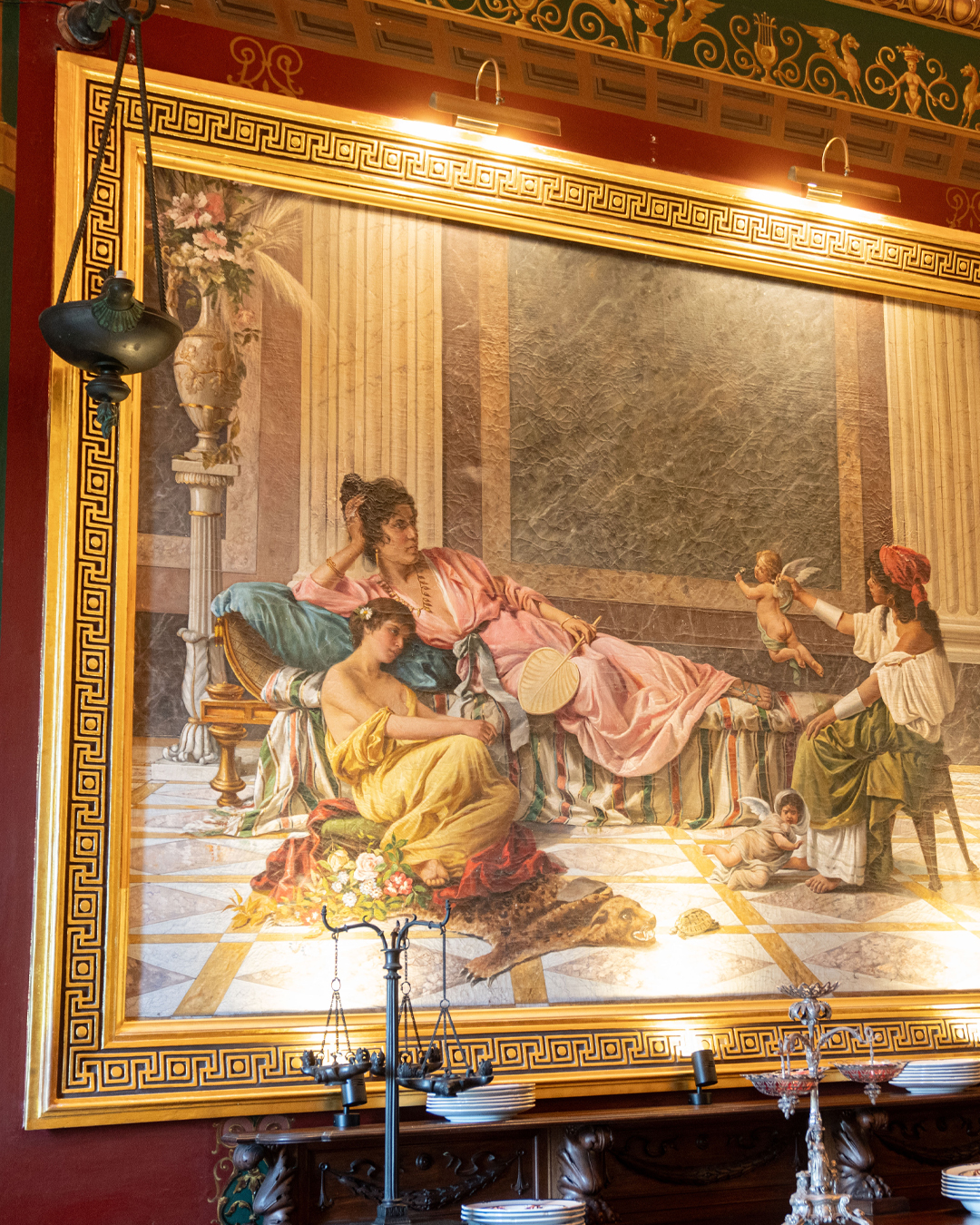 The marchesa sits as a Roman goddess in one canvas, surrounded by attendants. In the other, a young woman swings while admirers watch. Both scenes feel plucked from ancient Pompeii - which isn't far from the truth.
In 1901, Giuseppe Scicluna sent his architect, Annibale Lupi, to the actual ruins to photograph original frescoes. Those became Filippo Venuti's reference for these two paintings, considered among his finest works.
Here's the detail that makes them extraordinary: many of the women weren't imagined. They were local Naxxar women, faces Giuseppe knew and wanted preserved. We're still working to identify them all. Art, yes, but also a love letter to the village.
#FoodieFinds #PalazzoParisio #PalaceLife #visitpalazzoparisio