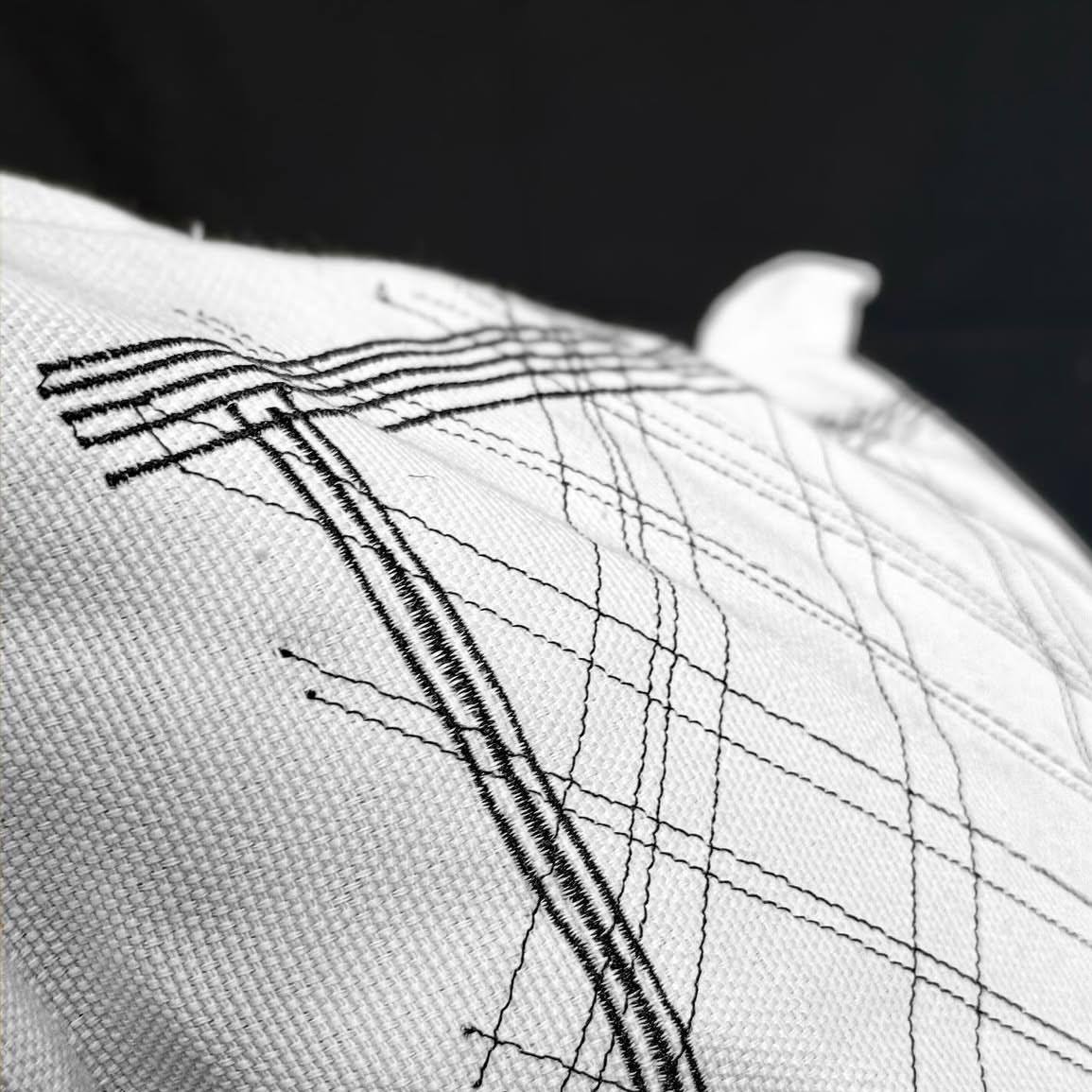 A tribute to Salvatore Fancello, a Sardinian artist renowned for his sensitivity to materials and the evocative power of his mark-making. The scratched lines on clay are transformed into threads stitched onto canvas:
embroideries that resemble contemporary rock carvings, capable of evoking a profound sense of belonging to the land, to memory and to the artisanal gesture.
Alongside the 50×50 cm square cushions, created in 2019, the new 60×90 cm rectangular series expands the scale of the narrative, transforming the marks into a narrative map.
Find out more about the@g._onnis cushion collection at TRADEprivé