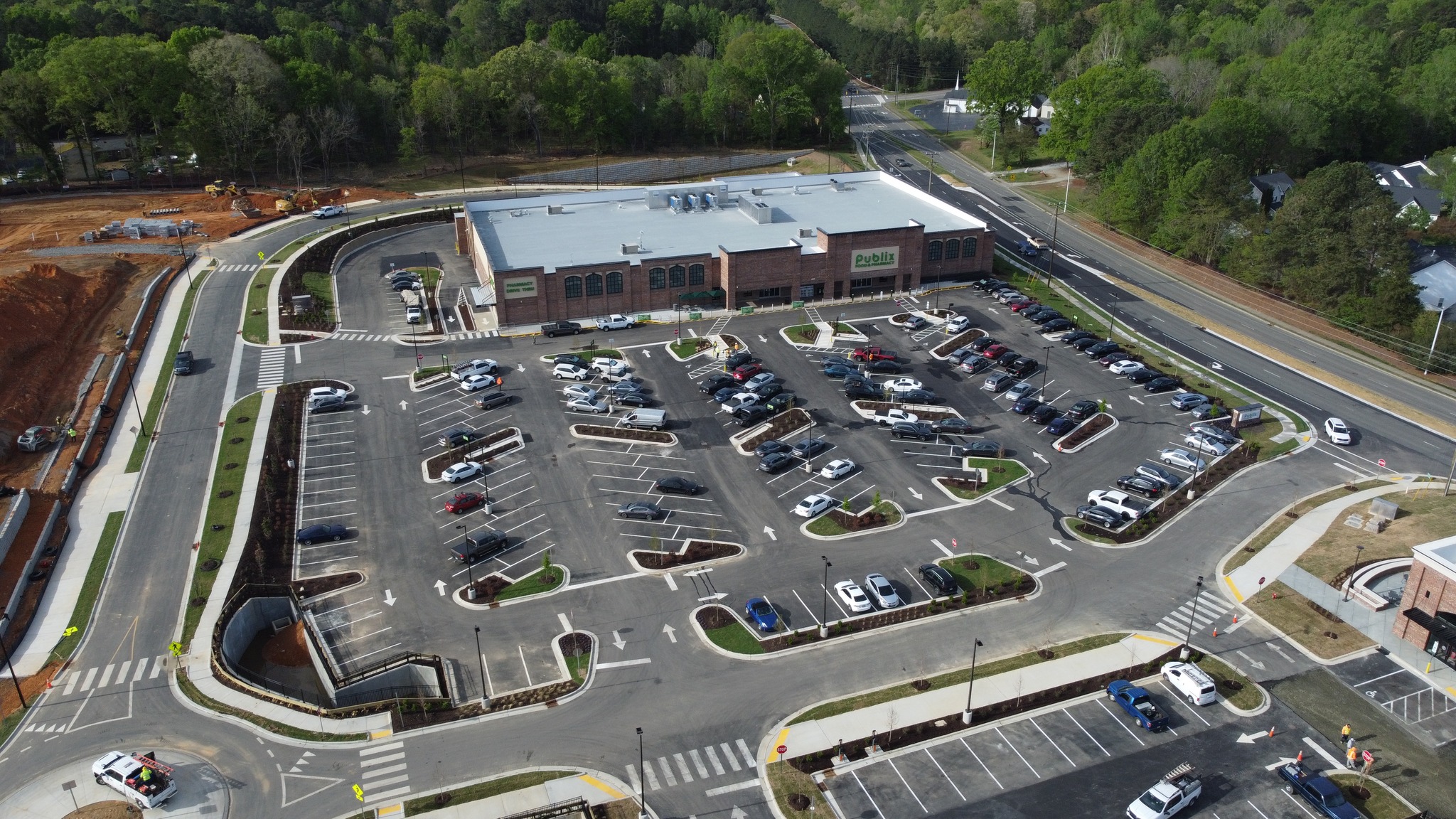 Hiscutt & Associates, Inc. proudly presents the opening of the Latta Park Shopping Center, located in Durham, NC on April 11th, 2026.
The Latta Park Shopping Center is a thoughtfully designed retail destination anchored by a custom 41,990 square-foot Publix store. The development totals approximately 54,990 square feet, including 13,000 square feet of additional retail shop space, and is part of a larger mixed-use community that enhances its accessibility and appeal.
Architecturally, the center features a timeless aesthetic, with most exterior walls clad in brick complemented by refined stucco accents. Elegant arches crown the storefronts, add visual interest and a cohesive design language throughout. Spandrel glass is incorporated across both the Publix and adjacent retail shop façades, contributing to a polished, modern look.
Sustainability is a key feature, with the retail shops powered by rooftop solar panels. A thoughtfully designed service court discreetly houses utility meters, grease traps, recycling, and garbage dumpsters, maintaining a clean and organized appearance. Visitors can enjoy a small amenity park adjacent to the retail spaces, featuring a nature walking trail and a fenced-in cornhole area, making the center both a shopping and community gathering destination.
https://www.hiscutt-aia.com/post/latta-park-shopping-center-opening
Opening Day photo by Publix Super Markets, Inc.