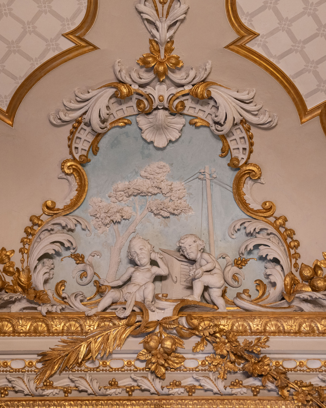 Four stucco scenes run along the study's cornice, each one a small autobiography in plaster.
Giulio Moschetti carved cherubs exchanging a cheque - the Scicluna bank was the first in Malta to introduce them, though locals mangled the pronunciation into "cisk," which stuck as the family nickname and later became Malta's beloved beer.
Other putti conduct banking business, naturally. One pair makes a telephone call, because Giuseppe owned one of the first telephones on the island - useful only for calling the one friend who also had one. The family coat of arms appears too, repeated throughout the house in different forms.
Some people commission generic decoration. Giuseppe turned his ceilings into a personal diary. Come see them for yourself.