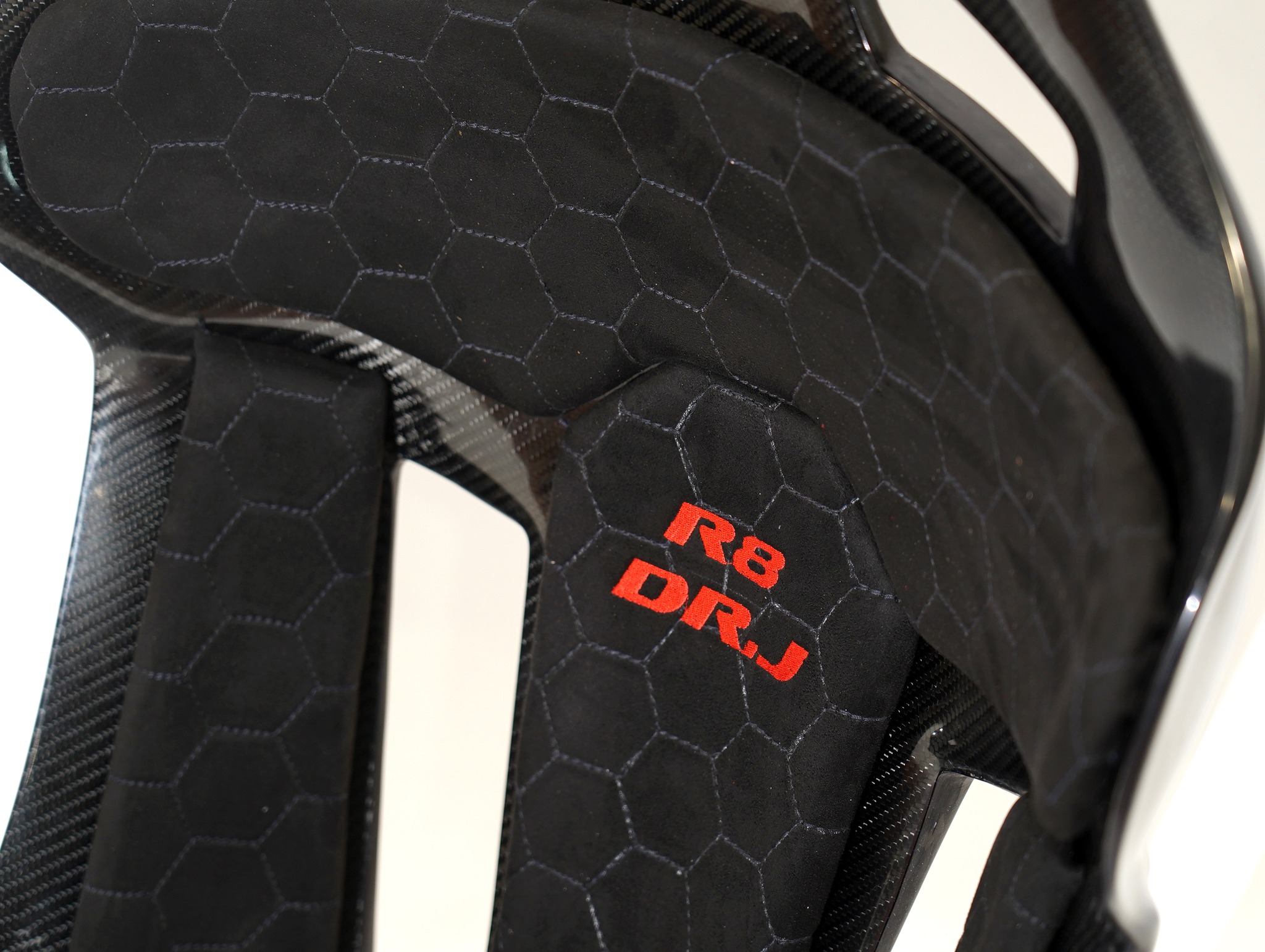 Rise to new heights with KevMannz's Carbon Fiber Bucket Seats, expertly crafted with GT-Max, Audi R8 plug&play rails and a slider kit.
Amplify your drive with bespoke black Alcantara padding, featuring a refined honeycomb stitching pattern and subtle logo embroidery on the headrest and backrest padding, and discover a driving experience that's truly elevated.