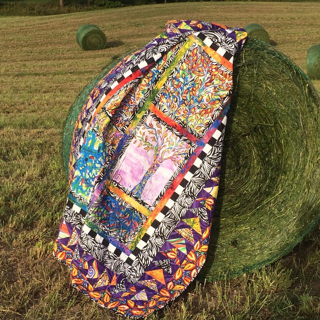 Fresh hay bales make a great backdrop for this Tree of Life quilt. #redredbobbininc #quilt #colourfulcontemporary #treeoflife