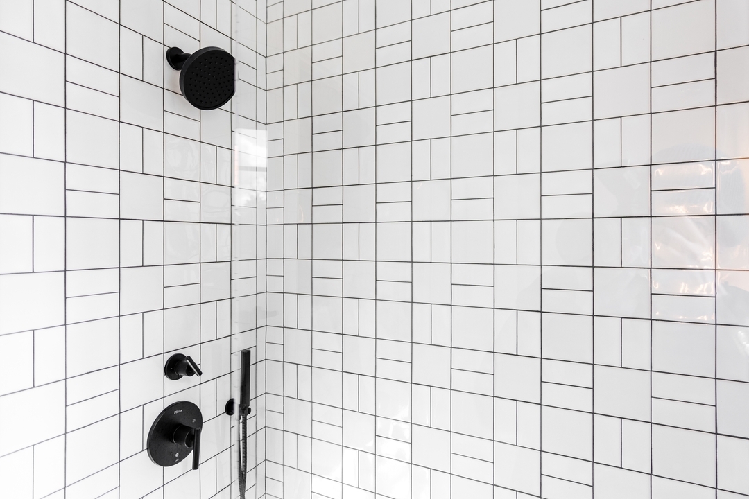 Dreamy shower vibes! 🚿✨ Our latest remodel features a chic basketweave tile pattern and sleek black plumbing fixtures.