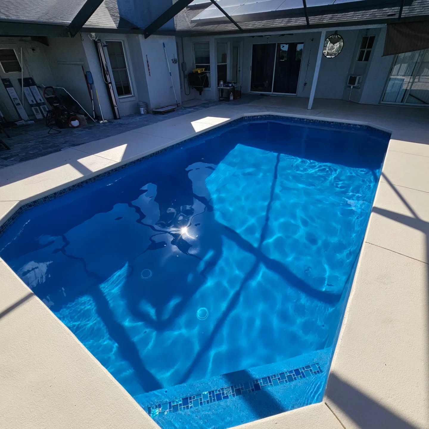 Azure Pebble and Glass Tile on this renovation. When installing glass tile on the wall, we install it on the steps too,  adding extra detail and dimension to the steps, especially with the long bench at the shallow end of this pool.
