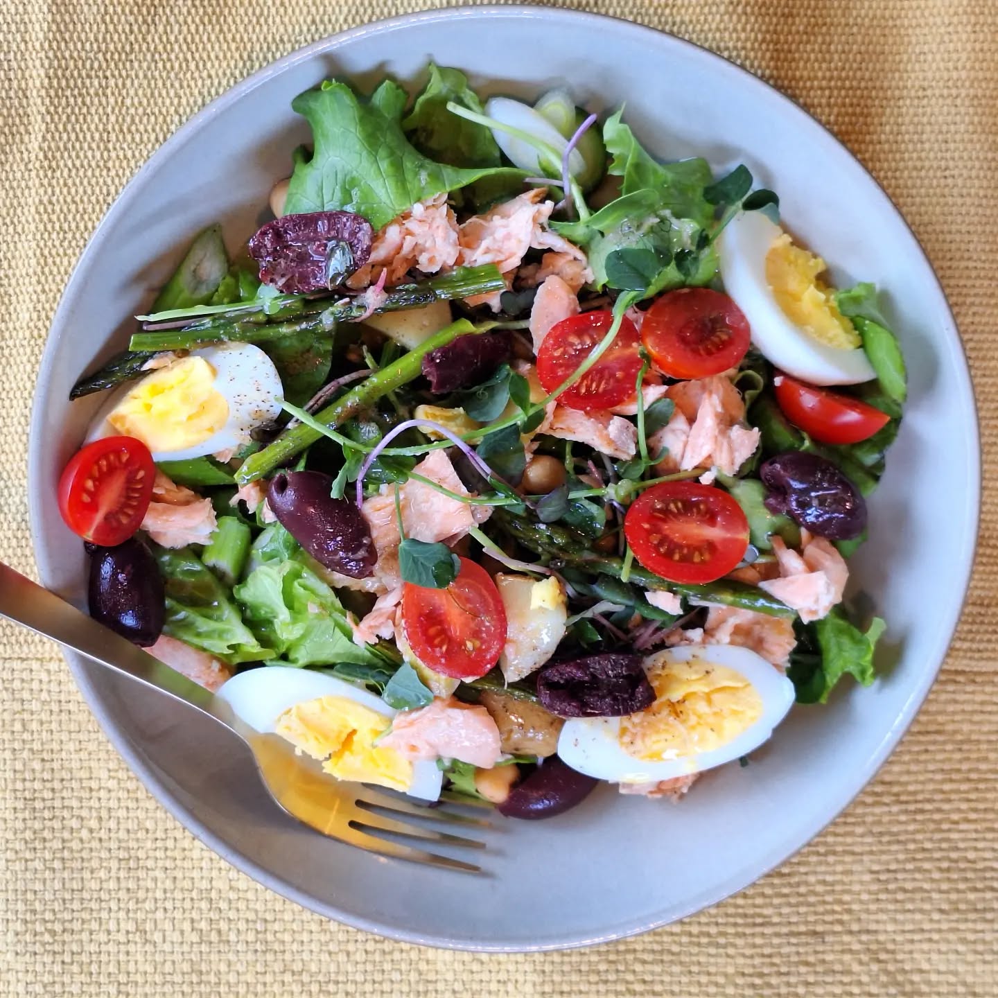 My take on the "salade niçoise" for lunch today: leftover salmon, a hard-boiled egg, greens, cherry tomatoes, black olives, new potatoes, chickpeas, asparagus, and sprouts with a red wine, Dijon mustard, garlicky vinaigrette.