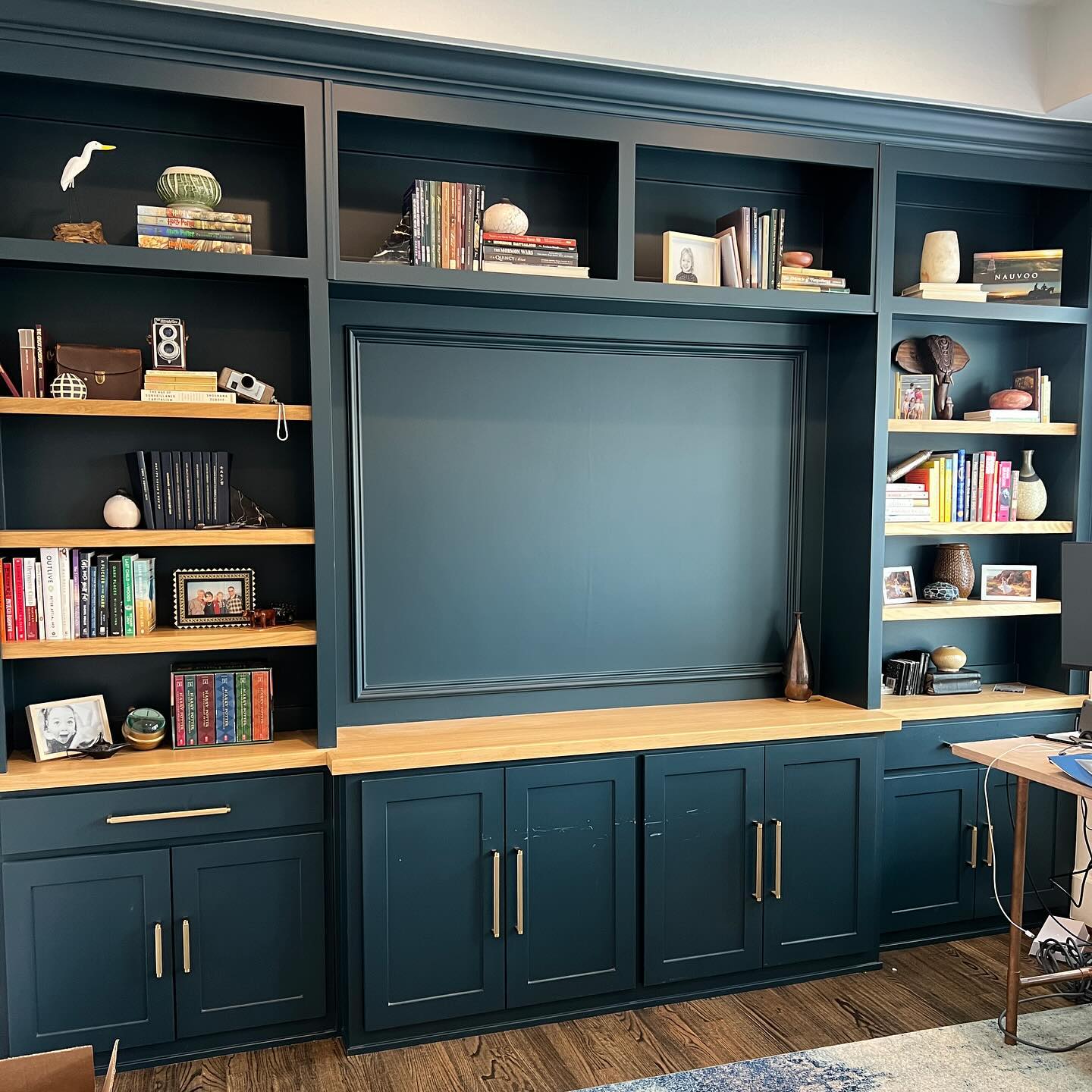 Pro-tip for an amazing home office…
Make it personal✨. Dig deep, look through those sentimental storage boxes, and absolutely ditch the generic art. Print photos of your loved ones, or favorite memories, or even favorite places that are actually meaningful to you. Pull out and encase/frame those items that you just can’t get rid of, and put them to use! Now, it does take a bit of skill to work these items in a space without it looking like a yard sale (no one wants that). If you need help with that, let me know!
This is going to not only make your office way better to be in, but if/when others see your space, they will get to see the much more authentic and interesting reflection of you! Why be generic, when you could be wildly interesting?
In this home office, we incorporated the homeowners pottery collection within the book shelves. Some of which she made, some collected from their world travels. We also included a section of books written by his father, and then books that were meaningful to them. Photos of their kids and family members, plus vintage cameras made it even more fun. Such a great space now!