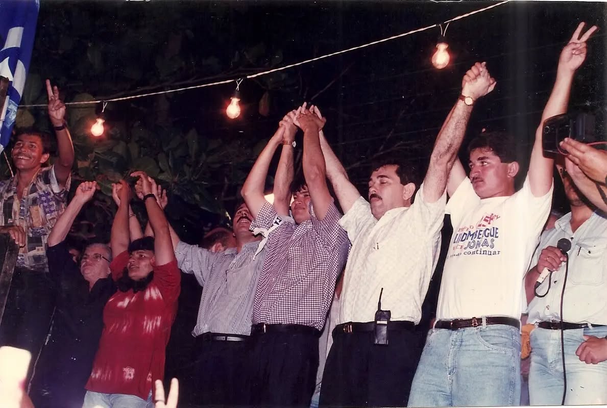 Há 28 anos!
As eleições de 1996 tinham como candidatos, pela situação, o jovem Lidembergue Souza Silva (Lindo), de apenas 21 anos, acompanhado do então vereador Jonas de Souza, ambos pelo Partido da Frente Liberal – PFL/25. A chapa oposicionista era formada por Maciel Nunes, que, à época, estava em sua quarta tentativa em chapa majoritária, a terceira como candidato a prefeito, e Nunes, ambos pelo Partido do Movimento Democrático Brasileiro – PMDB/15.
O comício em questão foi realizado na Rua Manoel Cirino Lira, em frente à residência de Antonio Veríssimo, local tradicional de comícios de seu grupo político.
Registram-se na foto autoridades como, o ex-prefeito e emancipador de Montadas, Antônio Veríssimo de Souza, o Prefeito José de Arimatéia Souza, o ex-Deputado Federal, Evaldo Gonçalves e o Deputado Federal, Álvaro Gaudêncio Neto.
Naquele pleito, os números reais foram: Lidembergue e Jonas tiveram 1.632 votos, e Maciel e Nunes obtiveram 858 votos. No entanto, devido a um erro de apuração do TRE/PB ao contabilizar os votos da urna 64, os números oficiais acabaram sendo: Lindembergue e Jonas 1.526 votos, Maciel e Nunes 937 votos. O juiz da Comarca de Esperança, Dr. Leobaldo, informou ao candidato eleito, Lindembergue, o problema na contabilização, o que levaria mais tempo para corrigir o problema, mas considerando que já estava eleito, Lidembergue seguiu a orientação de seu tio Arimateia deixando de lado a correção, visto já ter sido sagrado prefeito. Naquela época, Lindembergue foi o mais jovem prefeito eleito da Paraíba e o terceiro mais jovem do país.