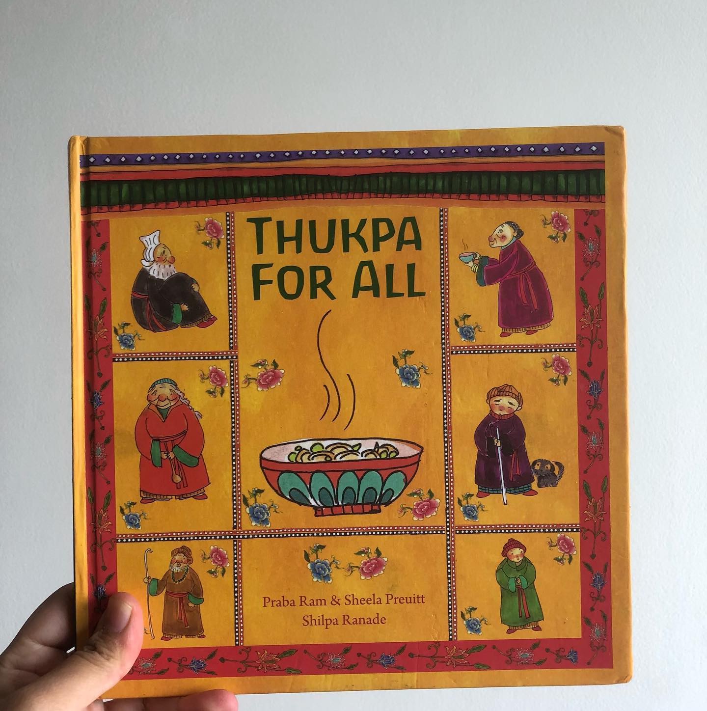Thukpa for All
By Praba Ram, Sheela Preuitt
Illustrated by Shilpa Ranade
Set in the beautiful valleys of Ladakh, Thukpa for All is a book that offers readers a glimpse into life in this stunning region. However, the true heart of the story lies in its portrayal of inclusivity, community, and food as a unifying force.
Early in the book, we gently become aware of Tsering’s visual impairment, but the authors skillfully ensure that it is never a barrier to his participation in daily life. Tsering moves through his day with ease, and along the way, he invites neighbors and friends to join him for a special dinner—his grandmother’s delicious, spicy Thukpa.
While the book touches on the challenges of living in a rugged, remote area, it is the warmth and generosity of Tsering’s friends and well-wishers that stand out. Each guest brings something to enhance the shared meal, adding to its richness.
Life in the mountains, though beautiful, comes with its own difficulties, and this is highlighted when a power outage occurs just as Abi-le is cooking. In this quiet, powerful moment, the story reaches its emotional peak, offering a deeper understanding of how Tsering experiences the world. For him, whether in light or darkness, his reality remains the same, and he steps in to help his grandmother finish preparing the meal.
The attention to detail throughout the story makes it a truly exquisite read. The illustrations, while rustic, provide an authentic representation of the region. What stands out most is the thoughtful sensitivity with which the entire book is crafted.
For children aged 4 and up.