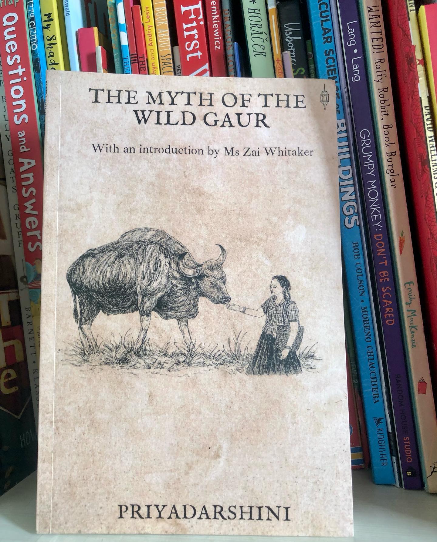 Book Review: The Myth of the Wild Gaur
By @jigsawsniffer
The Myth of the Wild Gaur addresses a critical issue— the delicate balance between nature and human activity, particularly in the context of the endangered wild gaur in the Nilgiris. As development continues to encroach upon natural ecosystems, species like the wild gaur are increasingly at risk of losing their habitats. The book places this environmental concern at the heart of a compelling narrative, led by the determined young protagonist, Theni.
Set in the Megham mountain of the Nilgiris, Theni, the daughter of the chief honey collector, belongs to a tribe that champions sustainability and respects the intricate balance of nature. Her community believes in a fragile, invisible web that connects all living things, warning that disruption could lead to catastrophic consequences.
The story begins when Theni’s class is discussing the wild gaur. Surprisingly, none of the children, including Theni herself—despite living in the forest—have ever seen the animal up close. Curious, Theni ventures to a lake where wild gaurs are known to drink, only to discover the lake has been reduced to a trickle. Upon investigation, she finds pipes diverting the water, threatening the ecosystem.
What follows is an inspiring tale of how Theni and her friends confront corporate greed in their fight to restore the natural balance. Theni’s unwavering courage and resilience stand out, as she refuses to be intimidated by the challenges ahead. Her bravery, even in the face of overwhelming odds, makes her a powerful and relatable character for young readers.
One of the book’s strengths is the portrayal of children as capable agents of change. None of the young characters are passive or easily discouraged; they persist in their mission to protect their environment, embodying the idea that children truly are the future.
Though illustrations are sparse, they are effective in complementing the narrative. The writing itself is vivid and evocative, skillfully bringing the lush Nilgiris and the Shola forests to life, immersing readers in the atmosphere of this beautiful and endangered region.
Ideal for kids aged 8+yrs