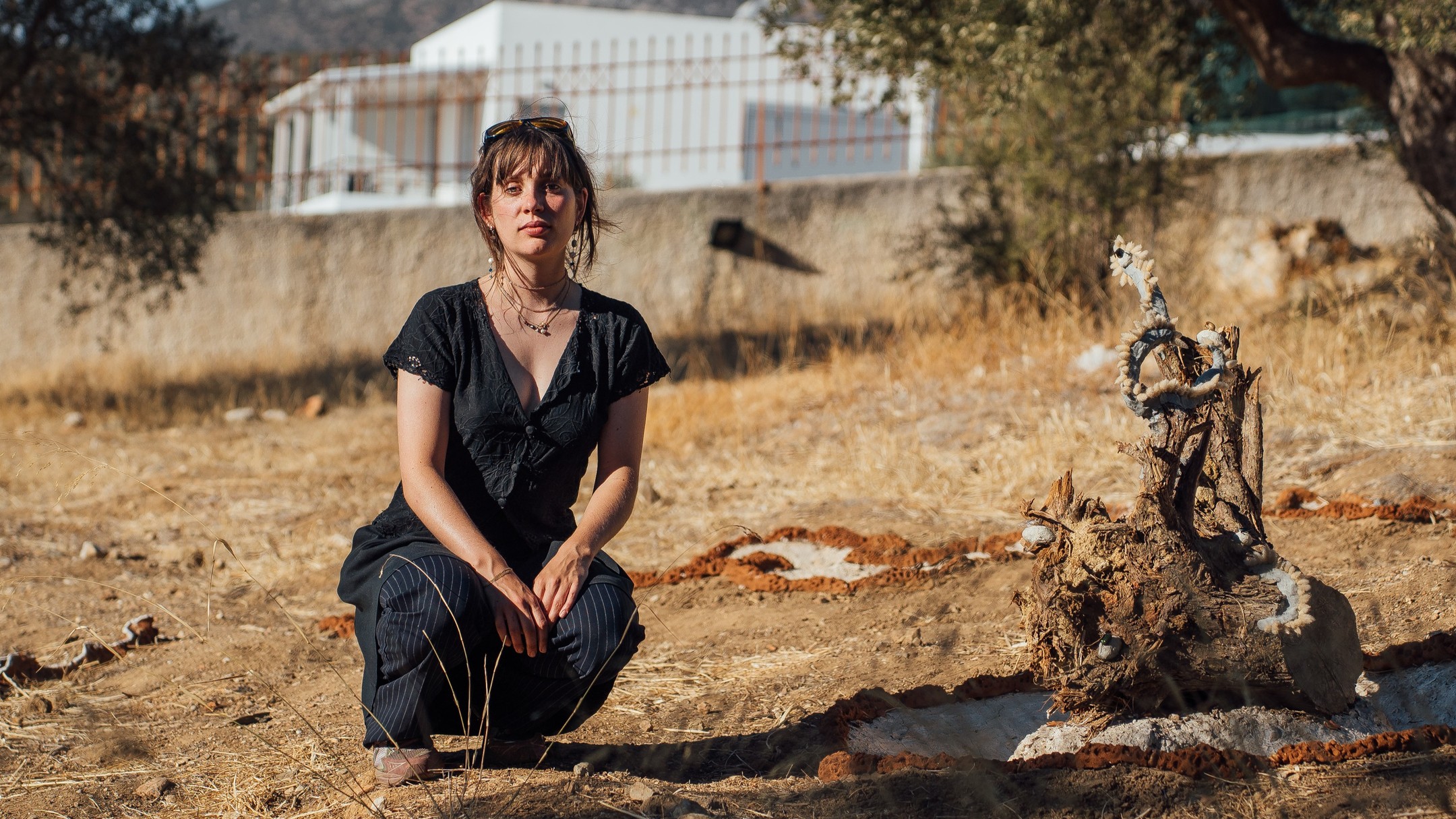 A spiral is a wounded cycle
In the olive grove of Villa M. you will find tiny spiral-shaped seed pods of button clovers scattered like confetti. A symbol of continuation in the palm of my hand, these pods capture how the cycles of this fire-ridden landscape aren’t simply circles—they’re spirals that break, heal and grow. Originally, I had planned to work with the concept of transformation through fire by making ceramic sculptures from local clay, but I realised that this environment itself was already a kind of natural kiln to its clay-rich soils. Wildfires have left their mark, transforming both the land and all its inhabitants like fired clay: beautiful and strong, yet precarious.
To honour this, I decided not just to create work about the land but to actually collaborate with it by making a land art piece amongst the olive trees. The shapes are inspired by environmental scarring from wildfires, the exposure of seeds and minerals that follow each blaze, and the local insects whose lives and habitats are at risk. Using only organic materials, such as clay from Mourteri beach and discarded olive tree roots from a nearby construction site, the piece will slowly return to the soil over time. The cavities are covered with a mix of water and flour adorned with ink made of caramelised pomegranate and ash from an area that burned in August. In them you can find local seeds that hopefully, as the rain washes away my work, will sprout in spring.
Silke Riis (Artist & Ceramicist)
Nestled between utopia and dystopia you'll find the slowly transforming works of Silke Riis. Deeply influenced by her own climate anxiety and the science-fiction subgenre “speculative evolution”, her practice revolves around imagining hypothetical species and alternative futures. To represent “uncertainty”, one of her key themes, she mainly works with transformative materials, and in Euboea she will work with locally sourced clay and the ancient technique of outdoor pottery firing to transform fragile clay into resilient ceramics. Originally from Copenhagen, Denmark, Silke has been based in the Netherlands since 2019 where she graduated from The Royal Academy of Art, The Hague.