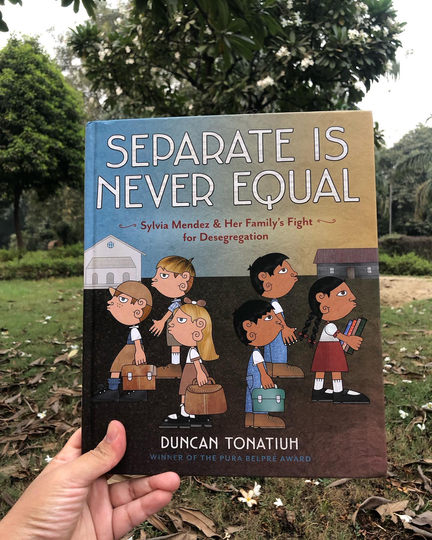 Separate is Never Equal
By Duncan Tonatiuh
Separate is Never Equal addresses the discrimination faced by Mexican-American children in California’s school admissions. The story follows Sylvia and her family as they move to Westminster, California, where Sylvia eagerly anticipates attending a larger school.
However, she and her siblings are denied admission, directed instead to a “Mexican school” with inferior facilities, initiating their family’s fight to end segregation in education.
The book presents moments of stark injustice, and brought shock and disappointment to my child who for the first time had to confront the reality of such inequality. It also prompts reflection on the privileges and opportunities we may often take for granted.
The illustrations, rendered in a folk-art style, are rich and evocative, enhancing the narrative’s emotional depth. The author’s note is detailed and insightful, providing valuable historical context.
This book is well-suited for children aged 6 and up, encouraging both awareness and empathy.