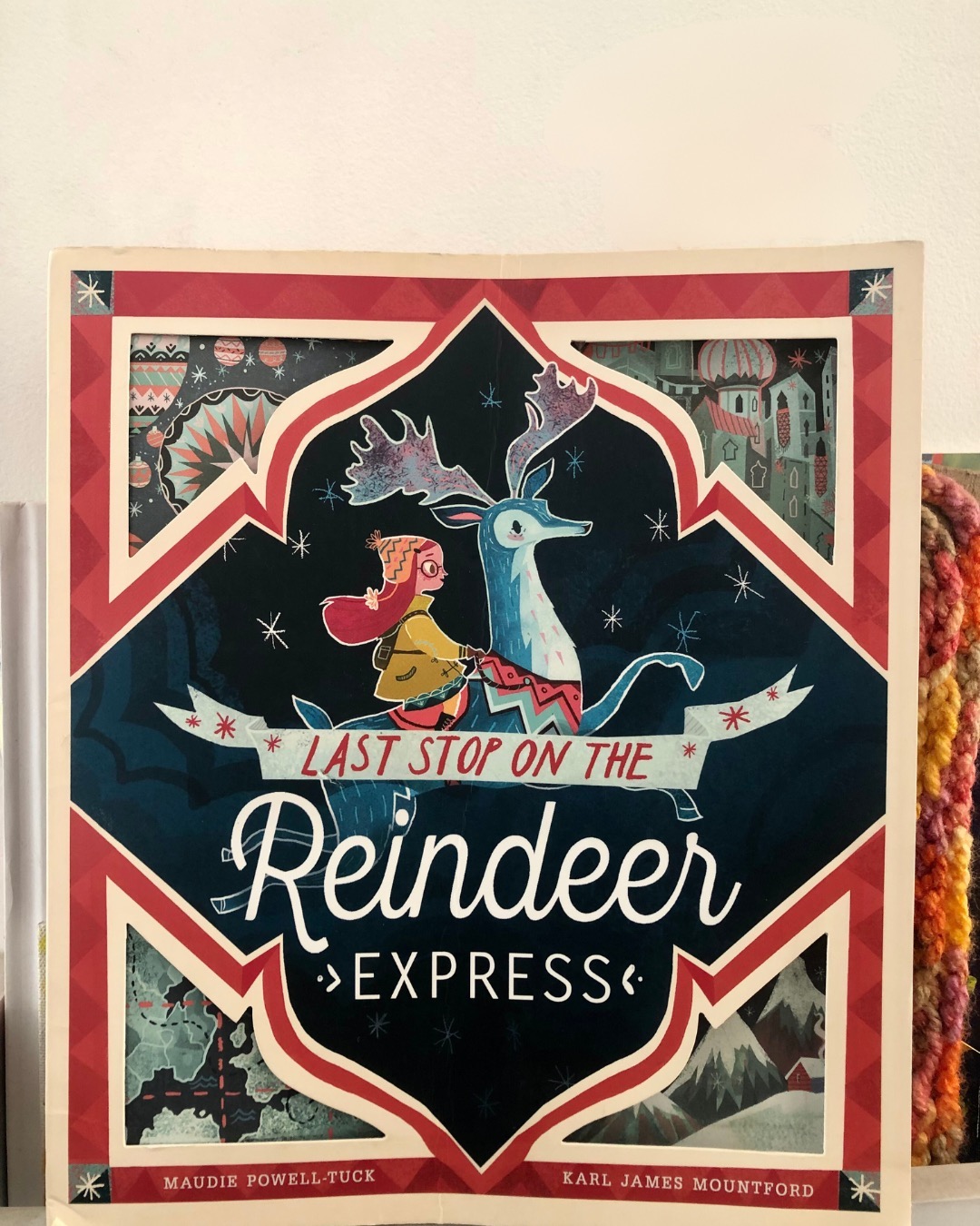 Last Stop on Reindeer Express
By Maudi Powell-Tuck
Illustrated by Karl James Mountford
Mia is excited to send a letter to her dad, but her mom gently reminds her that there may not be enough time for it to reach him before Christmas. Disheartened, Mia stumbles upon a magical post box at the market—the Reindeer Express.
On the other side of the post box lies an enchanting world of magic. Mia embarks on a wonderful journey aboard a reindeer, traveling through bustling cities and across vast oceans to deliver her letter and spend precious moments with her dad. The reunion is joyful, but all too soon, it’s time for Mia to return home.
The story subtly explores the complexities of family life during the holiday season. While the festive period often highlights picture-perfect celebrations, glittering decorations, and smiling faces, it’s a gentle reminder that not all families fit that mold. Many navigate their unique challenges, particularly during the holidays.
Mia’s story ends on a heartwarming note, perhaps due to the co-parenting harmony within her family. While family dynamics play a poignant background role, the heart of the story lies in the magic and warmth of the holiday season.
The illustrations are captivating, with intricate cut-work details that add an extra layer of wonder to the narrative. This book’s art truly enhances the magical experience, making it a delightful read for children and adults alike.
Ideal for children aged 4 and up, Last Stop on Reindeer Express is a touching tale of love, family, and the magic of Christmas.