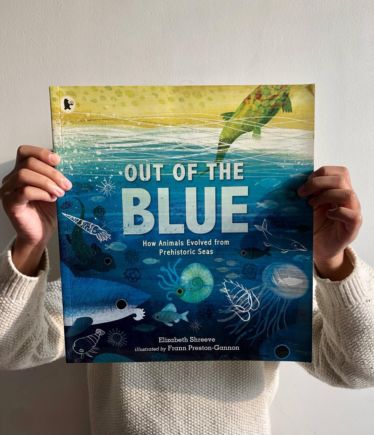 Out of the Blue: How Animals Evolved from Prehistoric Seas
By Elizabeth Shreeve
Illustrated by Frann Preston-Gannon
Have you ever wondered what connects hippos, dolphins, and sharks? Can you guess which two of these are most closely related? Out of the Blue answers this intriguing question by taking young readers on a fascinating journey through the history of life on Earth—from the ancient, mysterious seas to the land-dwelling creatures of today.
The story begins during the Archaean Eon (4-2.5 billion years ago) when life was purely unicellular, and gradually follows the epic journey of evolution that led to modern-day humans, who are still linked to ancient fish. The surprising revelation? Hippos and dolphins are more closely related to each other than to sharks! Mind-blowing, right?
The book’s double-page illustrations are not only visually stunning but also simplify the complexity of evolution, making it accessible and engaging for young readers. With vibrant, child-friendly artwork, the concept of evolutionary change comes to life in a way that captures the imagination and curiosity of children.
Perfect for curious minds, Out of the Blue is an engaging and informative read that helps children understand how life evolved from the depths of the ocean to the diverse range of animals we see today.
Ideal for ages 5+ yrs