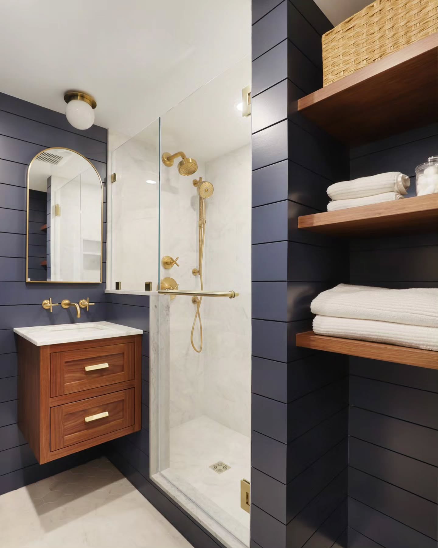 Client Requests for a small guest bathroom renovation. Convert tub to a shower. Blue shiplap. Maximize storage. Open feel. Timeless.
We maximized storage by creating a floor to ceiling nook with room for a hamper and floating shelves.
By making a nook instead of a closet, it helps the space feel open and also creates a unique design component, matching the walnut shelves to the custom walnut vanity. The custom vanity has drawers for storage, and the floating element makes the space feel airy.
Installing a wall mount faucet gives extra countertop space and maximizes the size of the sink.
The arched mirror is a recessed medicine cabinet for additional hidden storage. We opted to install a ceiling fixture instead of a wall sconce. This allowed us to get a tall medicine cabinet.
Marble tiles, brass fixtures, and a walnut finish create a timeless palette.
Every element of every space is intentional.
📷@dannycooney
#bathroomdesign #bathroomrenovation #interiors #interiordesign #renovation #remodel #construction #design #designbuild #customhomes #luxuryliving #millwork #woodwork #westchesterhomemagazine #westchesterliving #traditionaldesign #dwellmagazine #bhghome #lonnyliving