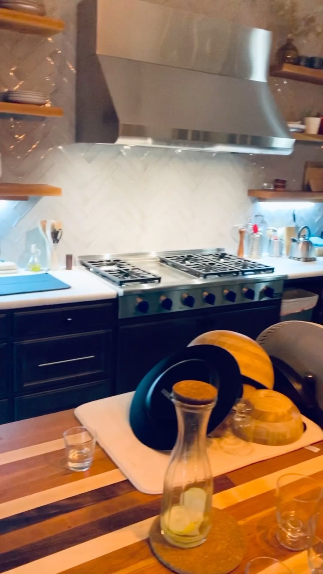 Epoxy countertops, butcher block island, floating shelves, and lighting. A year later, still loving this Kitchen.