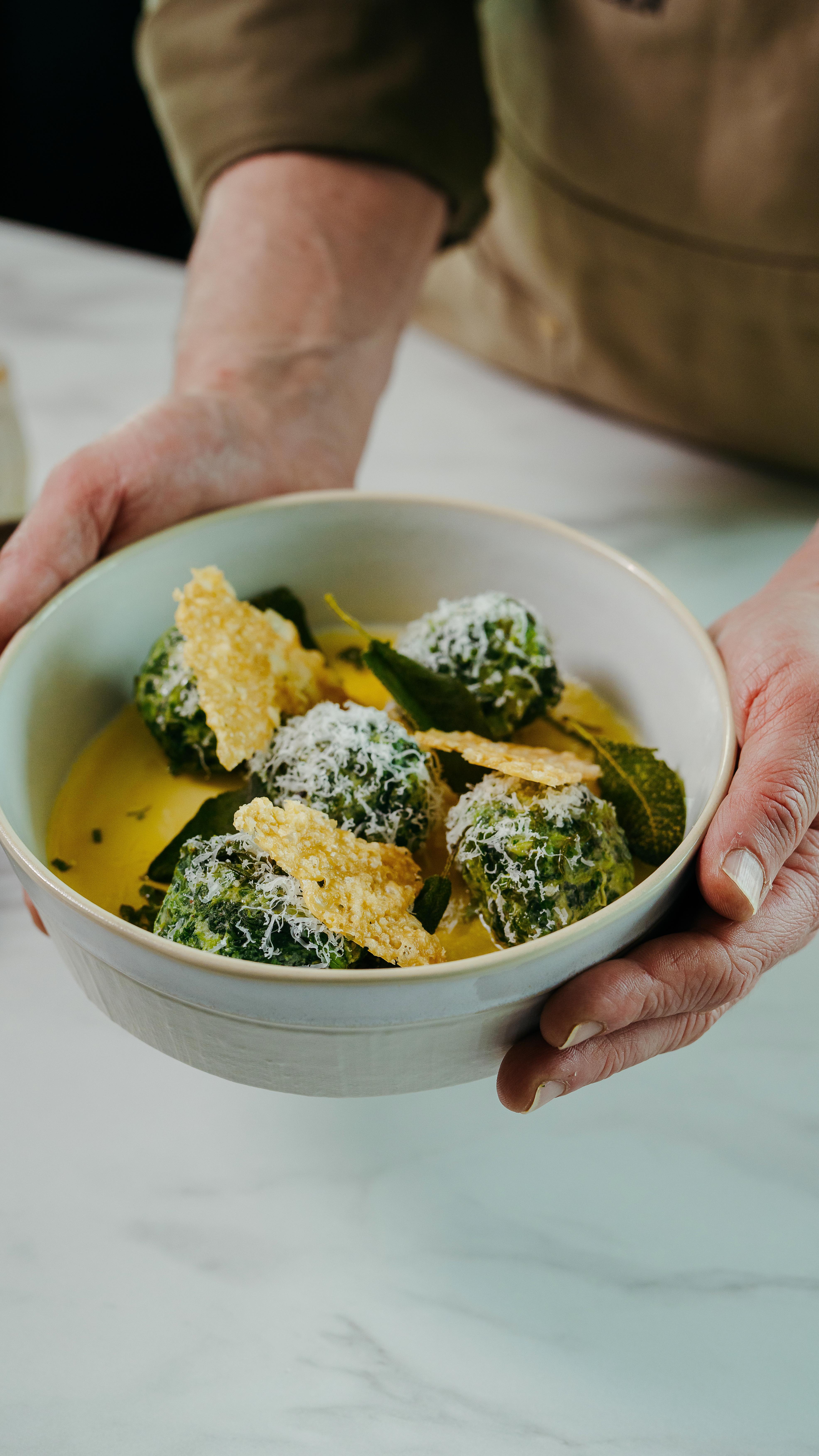 Malfatti. Letterlijk vertaald betekent dit in het Italiaans ‘mislukt’ of ‘slecht gemaakt’. Dit wordt ook wel de makkelijkste pasta ter wereld genoemd, omdat elke ‘kluns’ dit gerecht kan maken. In vergelijking met gnocchi en pasta is de Malfatti zeker niet oogstrelend, maar wacht maar tot je er een hap van hebt genomen, want het zijn de smakelijkste misbakseltjes die je in tijden hebt geproefd.
Blad spinazie 250 gr
Ricotta 150 gr
Geraspte grana padano 100 gr
Salie 7 gr
Eieren 1 st
Nootmuskaat 45 gr
Bloem 100 gr
Roomboter 100 gr
Garnituur 1 stuk
Peper/zout 1 gr
De bereiding:
1. Laat de spinazie ontdooien en knijp goed uit. Je hebt 1 1/2 kg uitgelekt gewicht nodig; hak dit grof met een mes.
2. Hak de helft van de salieblaadjes fijn.
3. Meng de spinazie met de ricotta, 200 gram Parmezaanse kaas, de gesneden salie, eieren, nootmuskaat, en peper en zout.
4. Voeg stapsgewijs bloem toe en meng tot er een stevige massa ontstaat. Misschien heb je niet alles nodig, of juist meer.
5. Maak ronde balletjes ter grootte van een golfbal.
6. Breng een grote pan gezouten water aan de kook en gaar de Malfatti op laag vuur tot ze beginnen te drijven, ongeveer 5 minuten.
7. Frituur de laatste salieblaadjes en smelt de boter.
8. Verdeel de malfatti op een bord met de gesmolten boter, Parmezaanse kaas en gefrituurde salie.
#wecanteen #bedrijfscatering #Foodbook #recept #receptidee