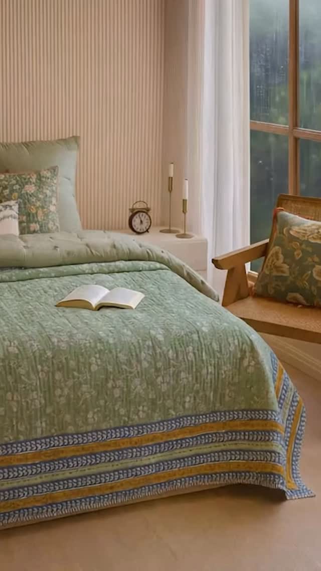 The rain taps gently on the window, curtains swaying with the breeze. Inside, the room is calm, a bed layered with soft, hand block printed quilts, cushions, and shams in soothing greens. Everything feels slow, still, and safe.
It’s the kind of morning where you don’t rush. You just listen, breathe, and stay under the covers a little longer