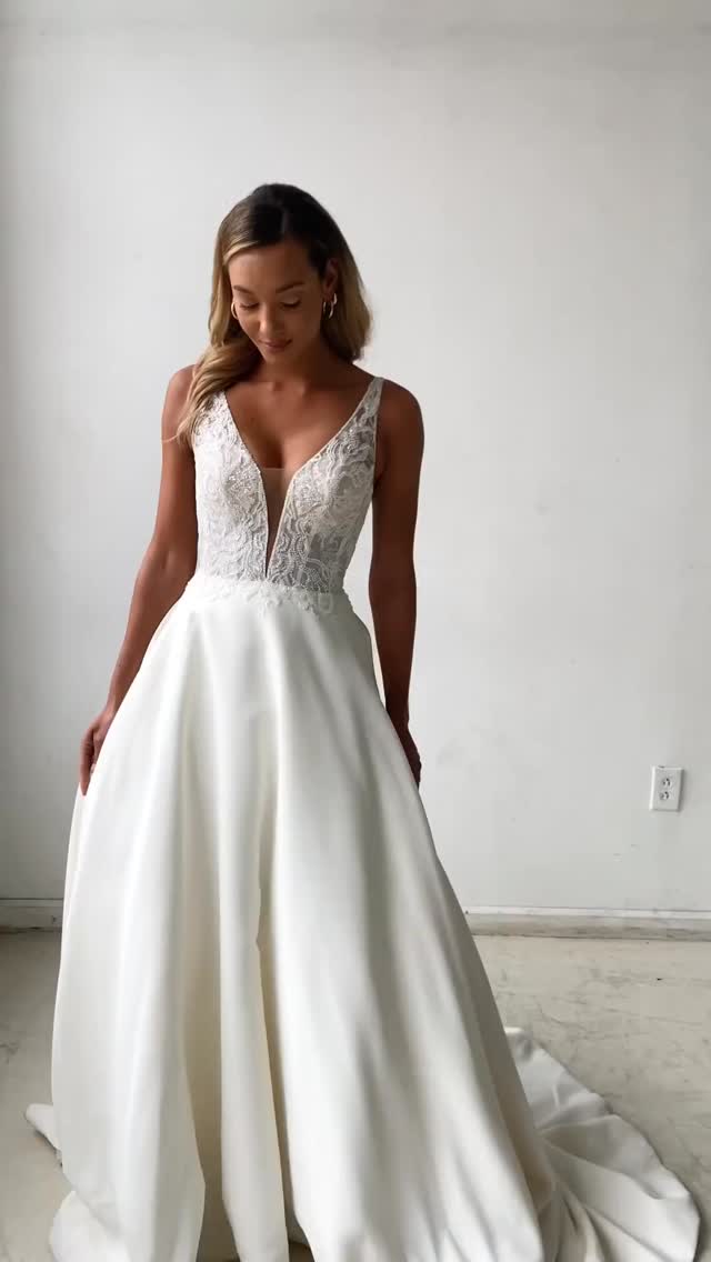 A dazzling take on a classic silhouette, this satin ball gown features a sexy plunging V-neckline with thin straps that give way to an open V-back. Unique appliqués of embroidered beading over a glitter tulle underlay create modern sparkle. The soft satin skirt is finished with pockets and buttons extending down the chapel length train. It’s paired with a matching cathedral length veil, available separately as 44276V. A raised neckline option is also available for this style.
@sinceritybridal - Style 44276
#bride2026 #bride #weddingdress #satinballgown #satin #plunge #vneck #glittertulle #matchingveil #pockets #yateley