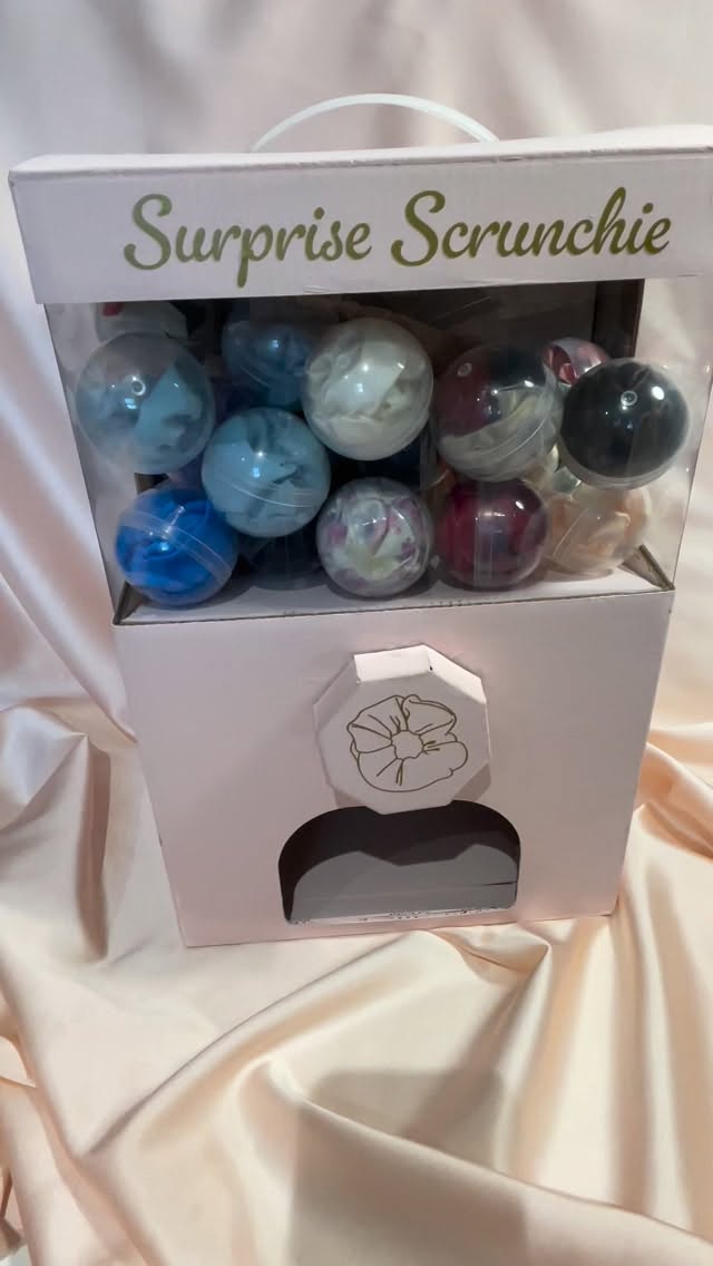 Meet the Itsy Bitsy Teenie Weenie Scrunchie Vending Machine-y! I’ve been looking for a capsule machine that would work with scrunchies *and* be light enough for me to carry to markets and events so was very excited when I found this cardboard one. After a bit of decoration, she has made her debut at Lewes Artists and Makers and will be coming with me to @craftyfoxmarket on the 7th and 14th December in London!
Video description- A pink cardboard capsule vending machine with surprise scrunchie text. Jo’s hand spins the wheel with a gold scrunchie outline and a capsule appears in the opening. Jo opens the capsule to show a deep red silk scrunchie. Audio says “I’m in love with you. I apologise for the blunt delivery but”