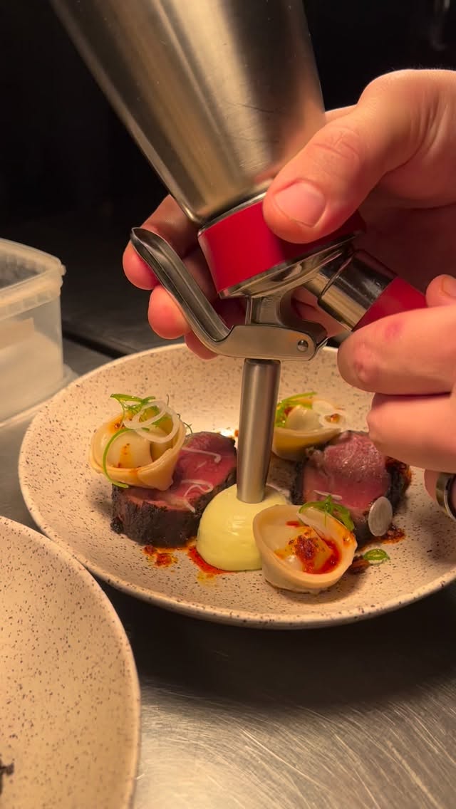 Szechuan Lamb & Dumplings
all the flavors from your favorite dumpling spot composed as a dish.
Beautiful lamb from @eat_more_lamb marinated in dark soy, Szechuan peppercorn and cumin grilled over hardwood charcoal. Crispy Dumplings with mushrooms and cabbage, our (undefeated) chili crisp and scallion espuma.
We’re just having fun out here…