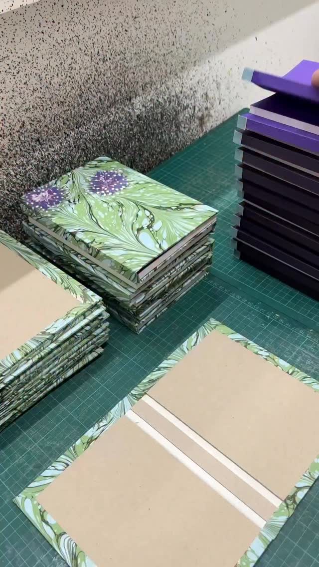 Casing-in! …Putting the books into the covers 🪻💜 Lined notebooks made with lovely Munken paper pages, purple @colorplan_papers endpapers, and hand-marbled floral covers inspired by the garden for @sarahravensgarden by me! See link in my bio for the full floral collection available to buy on Sarah Raven’s website. That reminds me I want to start growing some sweet peas this year!! ☺️