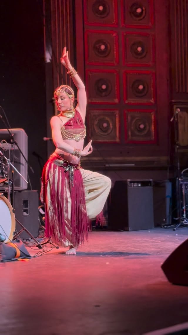 🔱 Shiva’s Gate 🔱
I choreographed this piece in 2016 in the holy city of Lord Shiva, Varanasi India. I was there for my 30th birthday meditating on my own impermanence, as Varanasi is a place auspicious to go to die, and hundreds of bodies are cremated on the ghats every day.
Shiva: the destroyer who absorbs everything back into himself with his wild dance, smeared in ash from the charnal grounds, wrapped in nothing but a tiger skin, hair matted with dreadlocks, drum beating wildly, serpents dripping from his limbs. The holy city of Varanasi mirrors his wildness. He’s not the god you bring home to meet your mother. And I loved him for it! So much so that I wanted to make a piece of art for him.
At the main burning ghat there is a flame that has been tended by a family of priests for thousands of years. It has never gone out, and it is the vehicle by which souls move from form into formlessness as their funeral pyres are lit. Essentially, it is the means by which they arrive into Shiva’s abode; the abode of pure unobstructed consciousness.
The premise of this dance in my creative process was that there is a Dakini (Dakinis are wild, sensual, liberated elemental forces), that lives in this holy flame, the ultimate devotee of Lord Shiva whose service is to send souls to him through her own burning passion to unite with him.
I hadn’t put this back on stage since around the time it was created, but finally, at long last, 10 years later, it happened.
#shaktitempledance #indianfusionbellydance #yoginipath #dakini