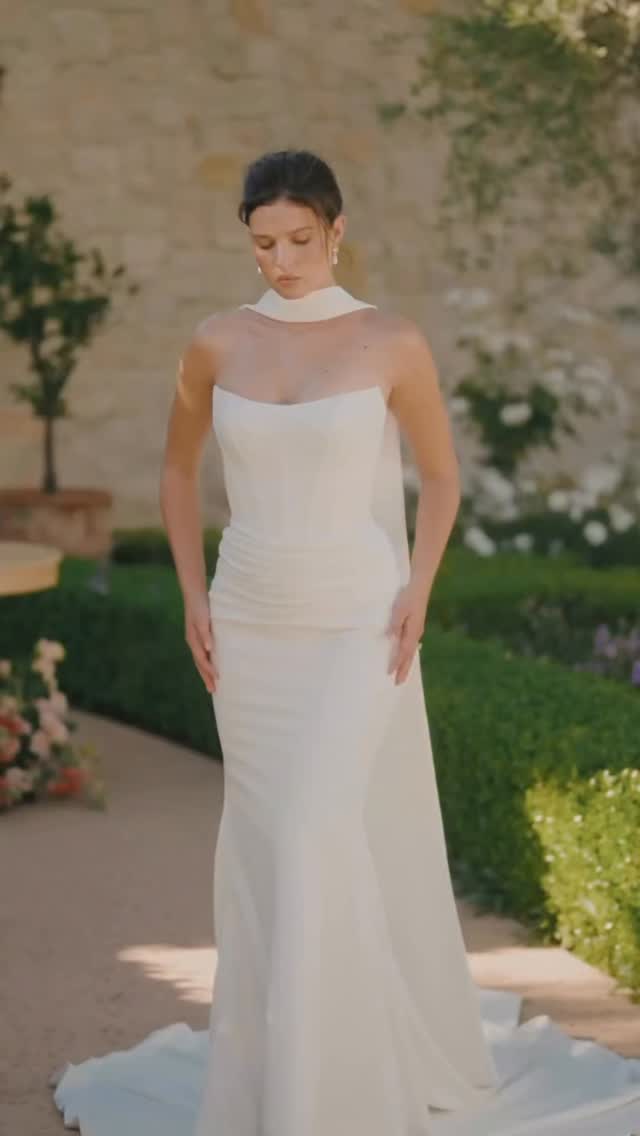 For the bride who loves a sleek moment ✨
Sculpted crepe, soft ruching, and a Basque waist create a beautifully elongated silhouette. Add the cape for a little extra drama down the aisle.