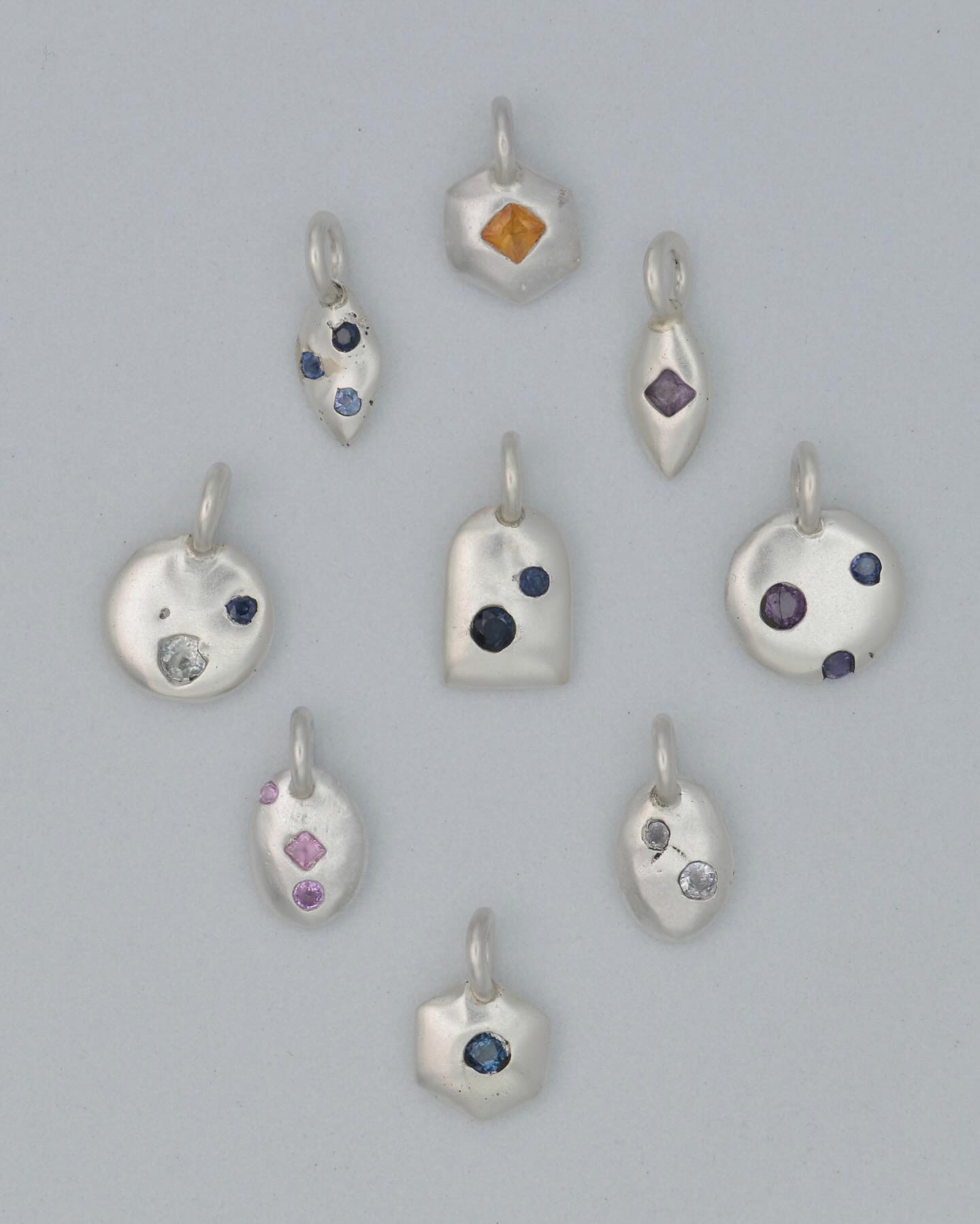 Introducing my newest series of sandcast sterling silver charms, each with sapphires cast directly in place. This process is one of controlled chaos—sandcasting captures raw textures and organic shapes, while casting gemstones directly into metal involves a bit of surrender to the unknown. Despite setting everything up carefully, the casting sometimes surprises me with stones shifting or breaking, or shapes coming out imperfectly. It’s been incredibly calming this week to work in this way, finding the beauty in those unexpected outcomes and letting go of the things that don’t work out.
Each pendant is shaped like a simplified amulet with its own symbolic meaning. The marquise shape could be an eye, seed, or vessel; the circle, a moon, wheel, or eternity; the oval, a skipping stone or mirror; the arch, a doorway or obelisk; and the hexagon, a symbol of foundation and strength. My hope is that anyone seeking a bit of protection, calm, or strength can find something meaningful in these pieces.
#castinplace #sapphirejewelry #amulet #charm #pendant #handmadejewelry #charmnecklace #sterlingsilverjewelry #rainbowsapphire #protectioncharm