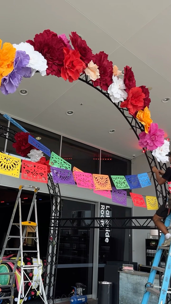 Last month we helped bring HOTA to life with a Day of the Dead themed event for the Student Excellence Awards, despite a last minute change in venue due to wet weather the night was one to remember. Working alongside the client we designed an entry tunnel adorned in large bright coloured flowers, flags and multiple neon skulls. On either side of the tunnel, guests were greeted by two 4m high inflatable sugar skulls. While inside the Lakeside room, our team dressed the tables with white sugar skulls decorated in pink, red and purple flowers which sat amongst a bed of candles 🌸🕯️