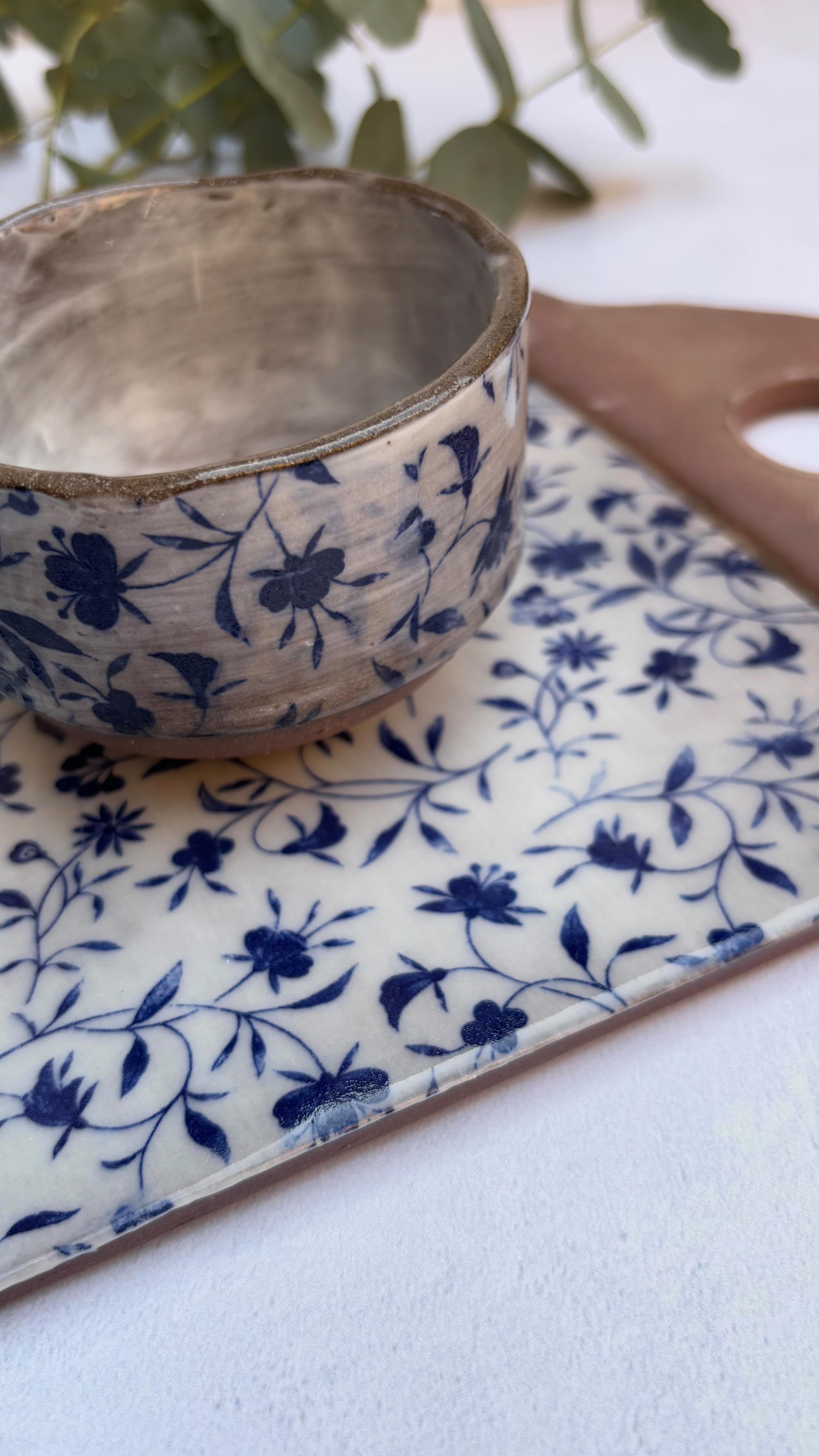 A cheese board with matching ramekin in blue, white and brown