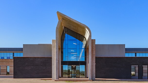 The Saldanha Bay Industrial Development Zone project is a large industrial estate development at the Port of Saldanha on the West Coast of South Africa. The project is the Access and Administration Complex for the development, with a footprint spanning 6,000mÂČ. The building features innovative green building elements, such as a stone-filled air plenum beneath the atrium floor for passive pre-cooling of the fresh air supply, achieving a 5°C reduction in ambient air temperature. Rammed earth walls blend natural local materials with modern functionality and offer excellent structural mass for insulation.
The layout is designed for modular expansion, allowing the client to grow the project to a much larger footprint as demand for office space increases when the IDZ fills with industrial developments over time.
#osmondlange #osmondlangearchitects #architecture #westerncape #buildingdesign #rammedearth #greenbuilding