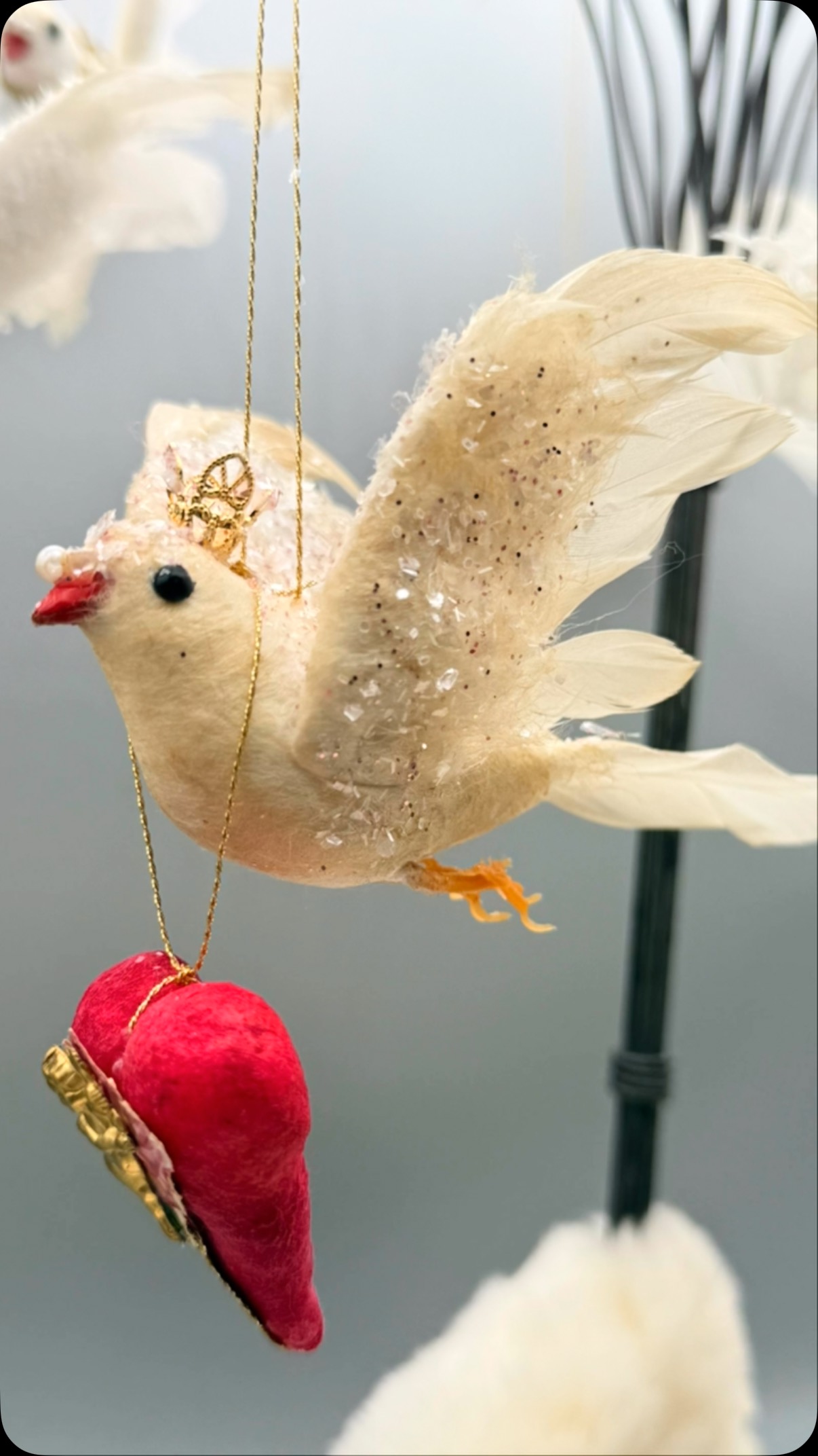 Happy Valentine’s Day! I’ve been busy crafting and creating a new form of art to add to my repertoire! Spun Cotton Ornaments! My first batch of “Love Doves” are available @grandleadermercantile Everett, WA. Stay tuned as I’m working on a bunch of new stuff and will start loading them on my website very soon! This is my soft launch introducing my revival of an old style of folk art, originating in the 1880’s in Germany. During Christmas time women would craft them from scraps of old cotton quilt batting and wrap the cotton around wire armatures shaped into different animals or little child figures. They would brush on a mixture of potato starch and water to stiffen the cotton. Once dry, they could paint on a simple face or use a scrap paper face to give them character. They would then adorn them with whatever other scraps of fabric, paper, ribbon or lace they had lying around. They would give them as gifts or decorate their Christmas trees with these adorable family heirlooms. Here I have used vintage premade spun cotton birds and then hand made some of the hearts out of spun cotton and hand painted them, then I add vintage ephemera or gold Dresden and adorn the birds with little crowns and glitter. The cotton I use is 60-70 year old medical cotton, and most of the items I use to decorate them are vintage scrap pieces. I have hoarded bits and baubles for over 10 years with the intention of creating them and I have finally decided it’s time to make these wonderful, one of a kind little sculptures. Stay tuned for more Holiday Spun Cotton. I’ve already got several Easter, Christmas and woodland animals completed, some of which are available right now on my website. I hope you’ll follow me to see what I create next! www.crooksycreations.com. #spuncotton #spuncottonornament #spuncottonfigures #spuncottonornaments #spuncottonchristmasornaments #spuncottonart #handmadeornaments #crooksycreations