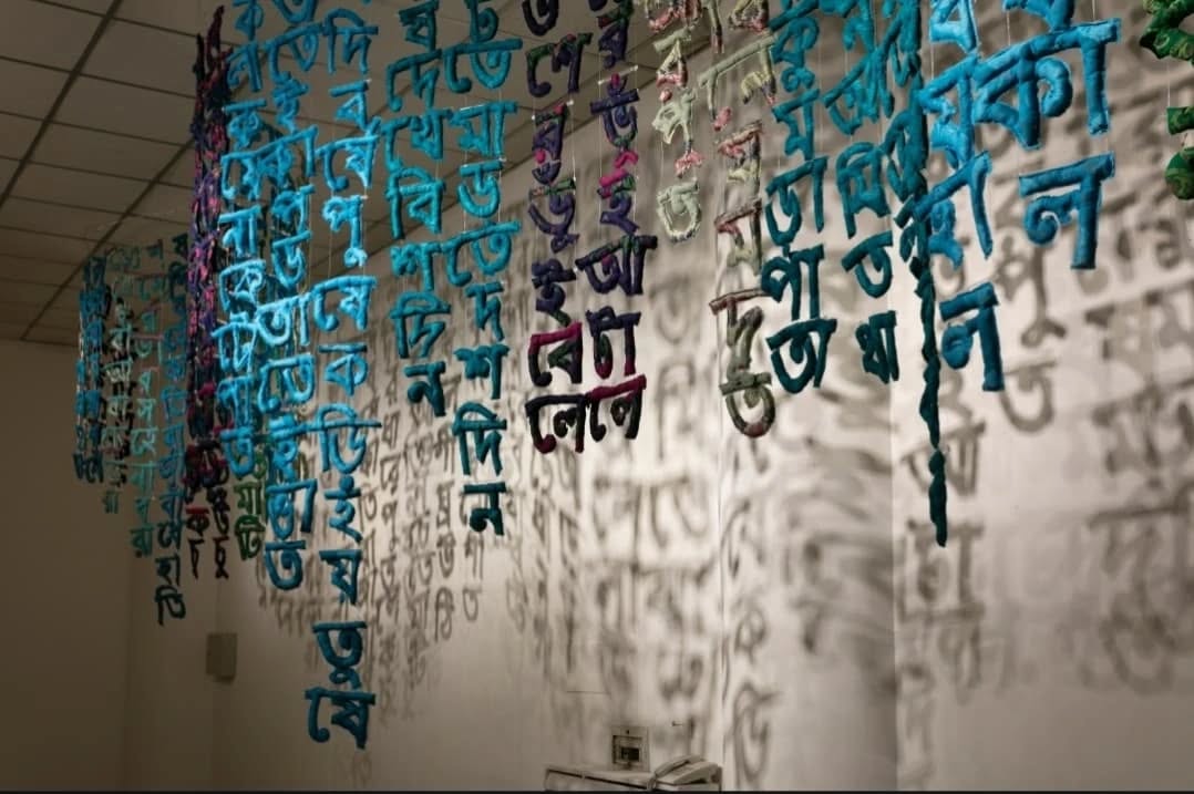 International Mother Language Day, established by UNESCO in 1999, commemorates Bangladesh’s Language Movement of 1952. This movement arose in response to the imposition of Urdu as the sole official language of East Pakistan (now Bangladesh) and led to the tragic events of February 21, 1952, observed as Language Martyrs’ Day. Recognizing the sacrifices made for linguistic rights, International Mother Language Day was introduced to promote the preservation and appreciation of mother languages worldwide.
On this occasion, we revisit বর্ণগীতি(Symphony of words), 2022-2023 by Najmun Nahar Keya from DAS 2023. Bengali script seems to drip from the ceiling as rain, or flow through space like a river, similar to how the words of Khana have flowed across time in Bangladesh. Khana was a poet and an astrologer active in Bengal somewhere between the 9th and 12th centuries, and her verses are among the earliest compositions of lyrical Bengali verse and tied to wisdom gleaned from observing nature. Like the Tangail sarees that Keya and her elder sisters used to craft these sayings into soft sculptural form, they are likely to become obsolete as these generationally passed down wisdoms are at risk of being forgotten.
Photographs of বর্ণগীতি(Symphony of words), 2022-2023 by Najmun Nahar Keya from DAS 2023.
Soft Sculptures Made from Antique Sarees.
Commissioned by Samdani Art Foundation.
Courtesy of the artist and Aicon Gallery.
@dhakaartsummit
@samdaniartfoundation
@nadiasamdani
@rajeebsamdani
@dhakadiana
@rux_q
@n.keya
@aicongallery
@swilin_haque
@sazzad1985
@iftekharnoor
#dhakaartsummit #samdaniartfoundation #dhaka #sylhet #art #artwork #DAS #exhibitions #contemporaryart #srihatta #artistresidency #sculpture #SAF